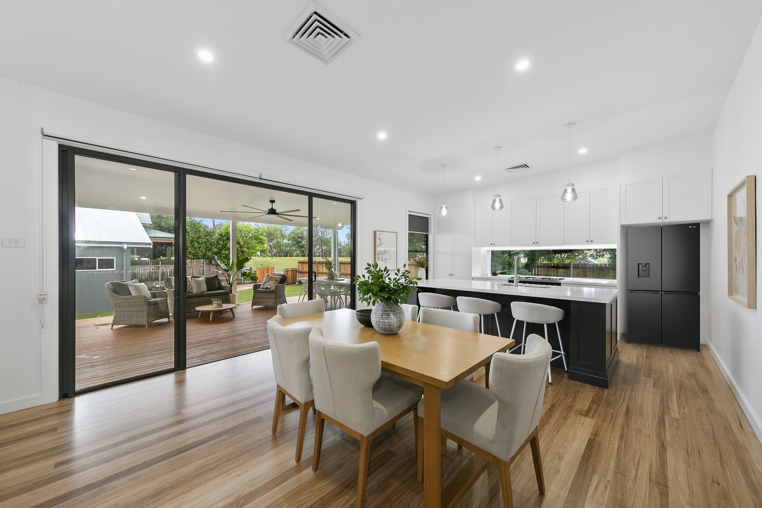 Modern open-concept kitchen and dining area with sliding glass door leading to a backyard patio with outdoor seating.