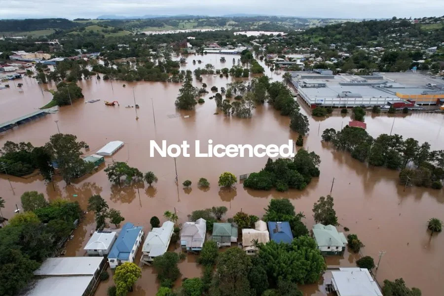 A flooded area with submerged houses, trees, and commercial buildings during a flood event.