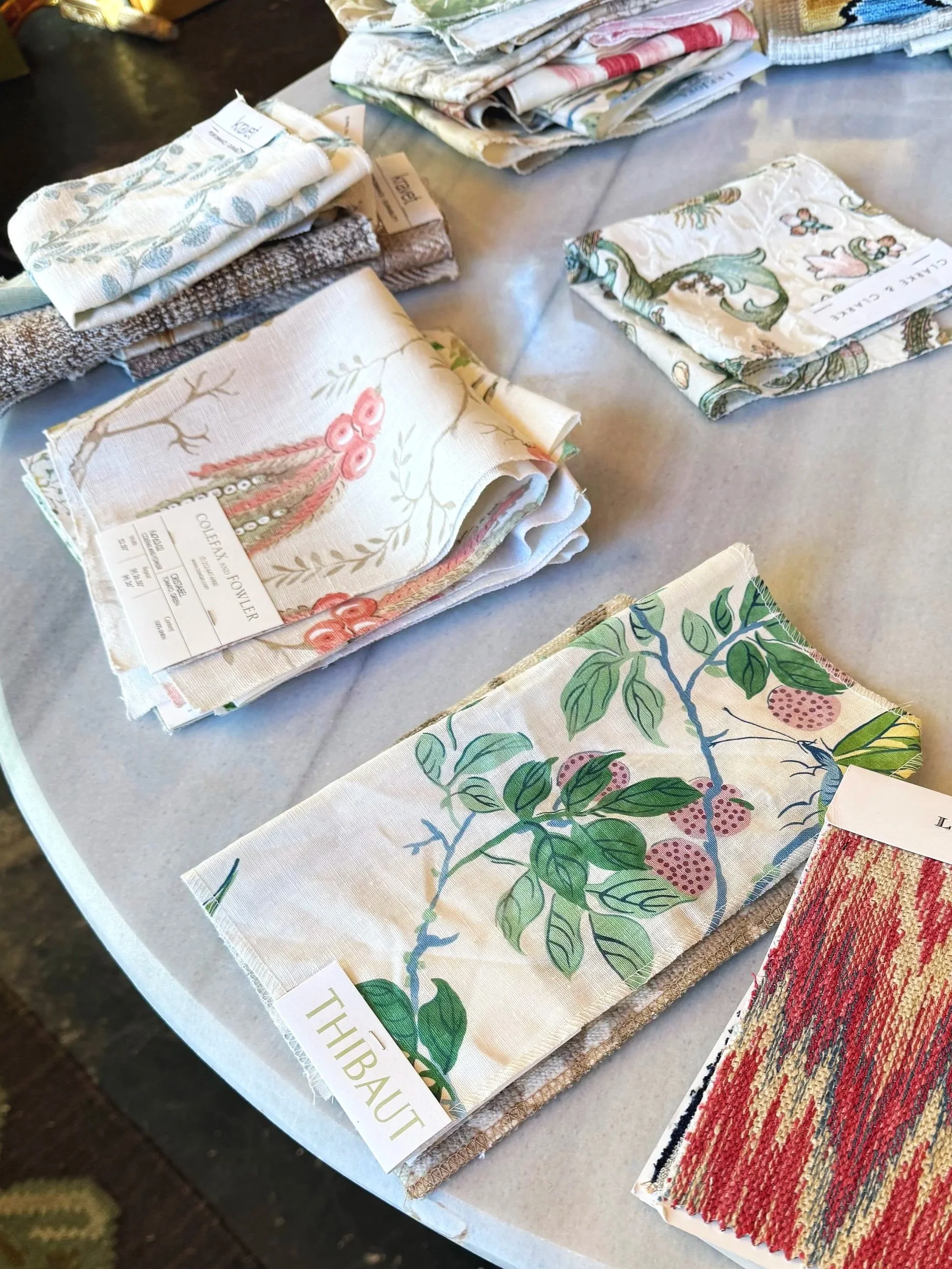 Display of fabric swatches with various floral and patterned designs on a table.