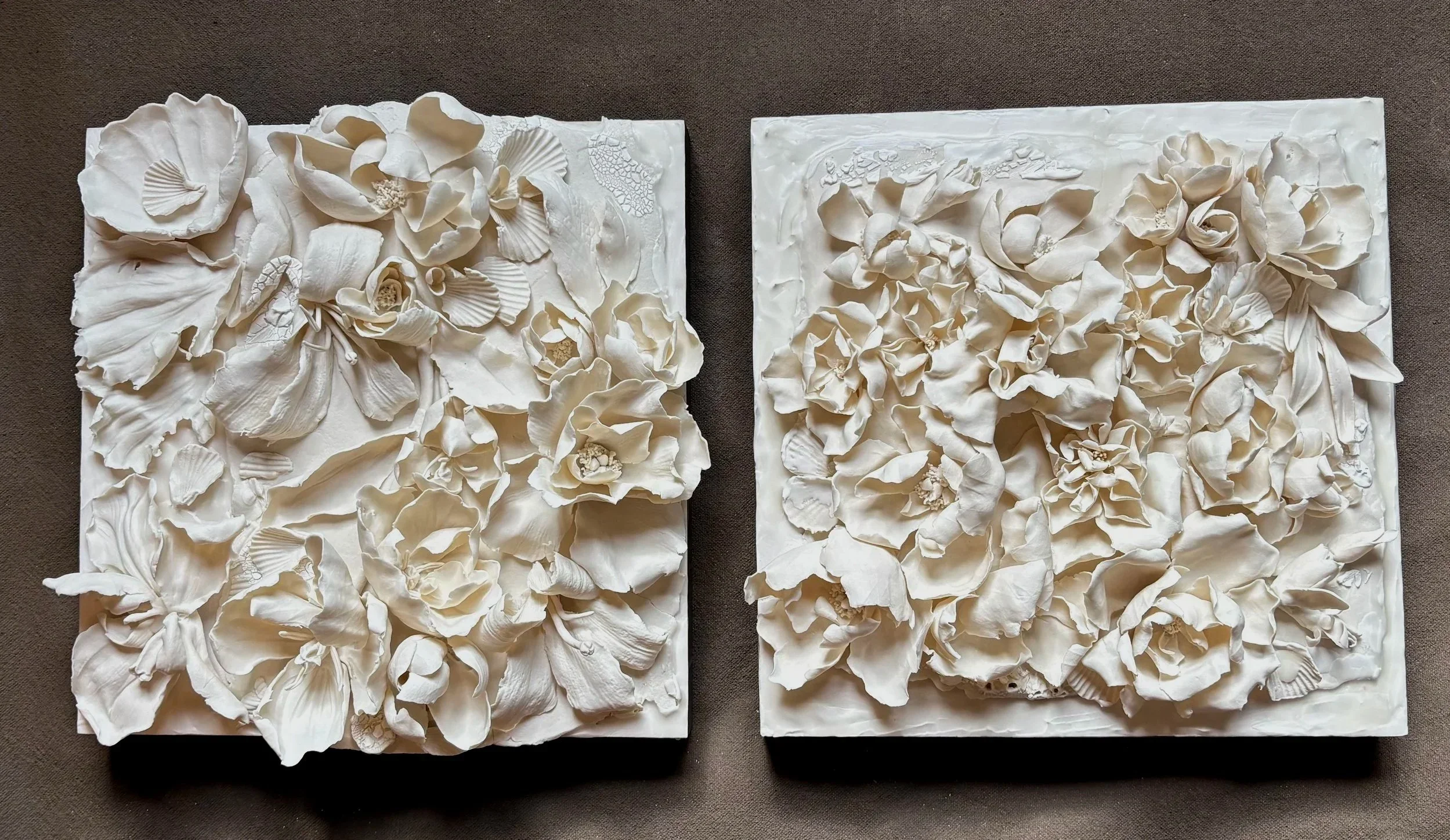Two white floral textured wall art pieces, each featuring intricate 3D flower designs on square canvases, placed side by side.