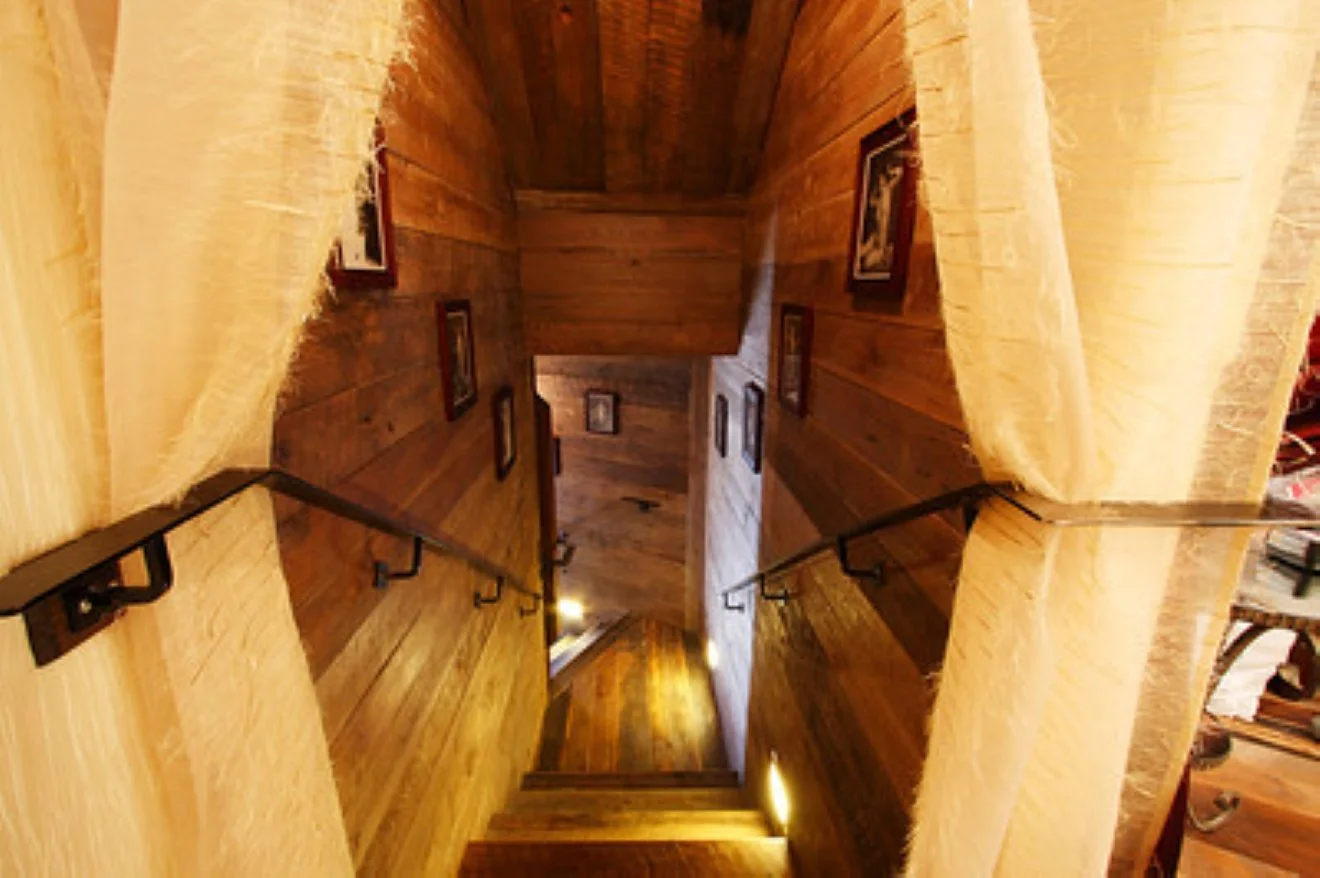 Historic wooden stairs with framed photos, descending from Needle & Thread to Tavern Law.