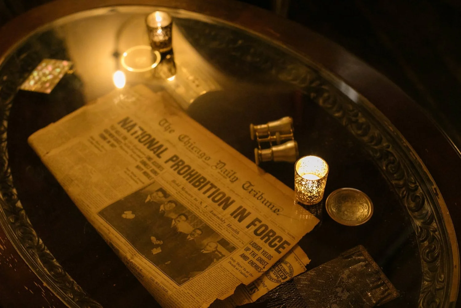 A Prohibition-era newspaper under candlelight on a table inside the Needle & Thread speakeasy on Capitol Hill.
