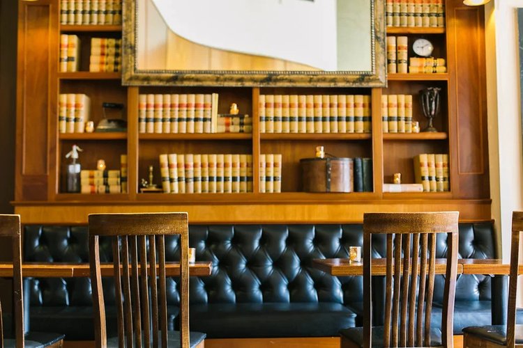 The library booth at Tavern Law, tufted leather seating under a wall of old law books.
