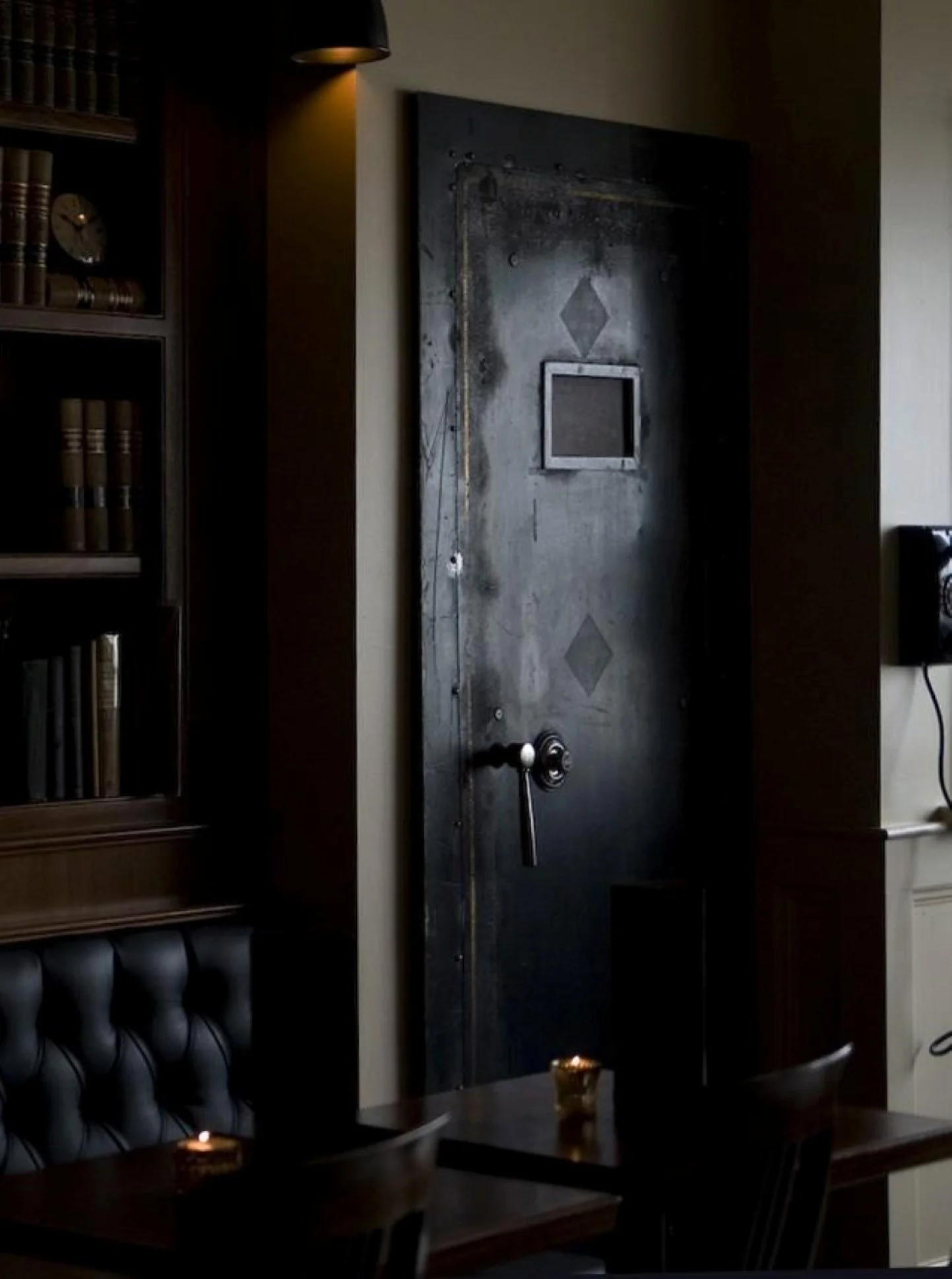 The vault door to the Needle & Thread speakeasy at Tavern Law, with the vintage wall telephone guests pick up to be let in.