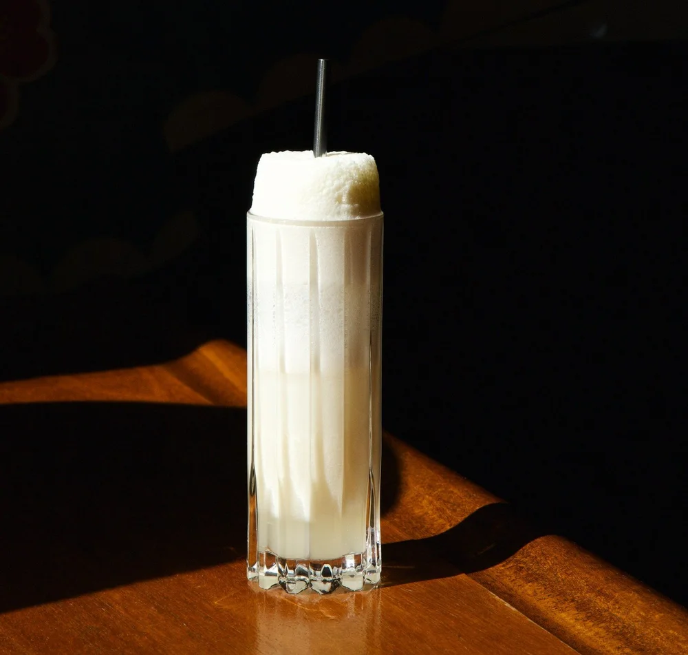 Foam-topped fizz cocktail served with a metal straw at the Tavern Law bar