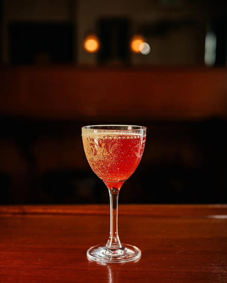 A ruby cocktail in a coupe on the wooden bar at Tavern Law on Capitol Hill.
