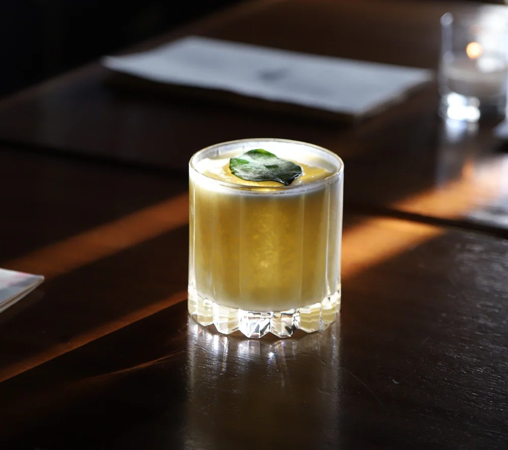 Golden craft cocktail garnished with a fresh leaf at Tavern Law on Capitol Hill