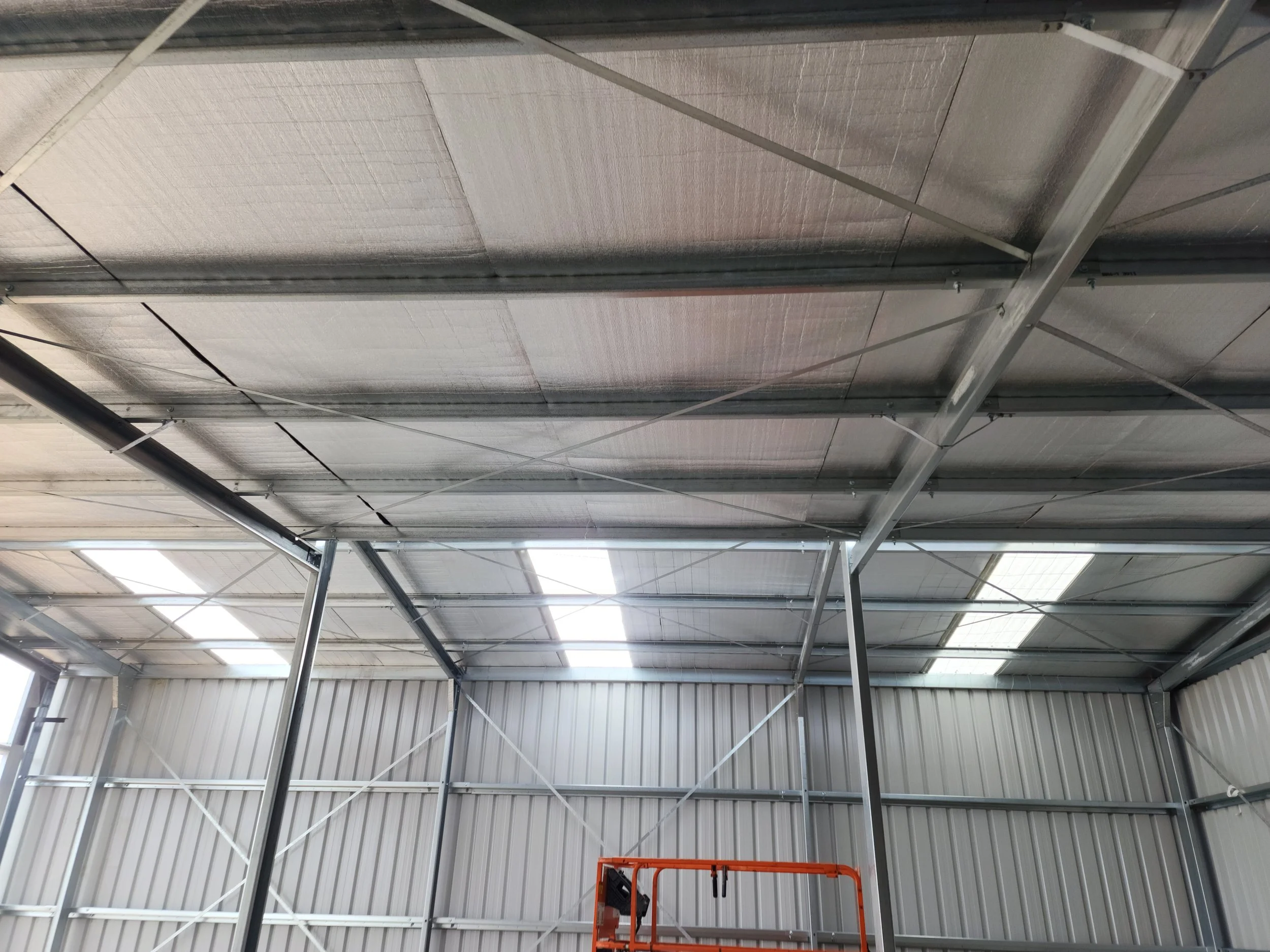Interior of an industrial shed under construction, showing a metal framework and ceiling panels.