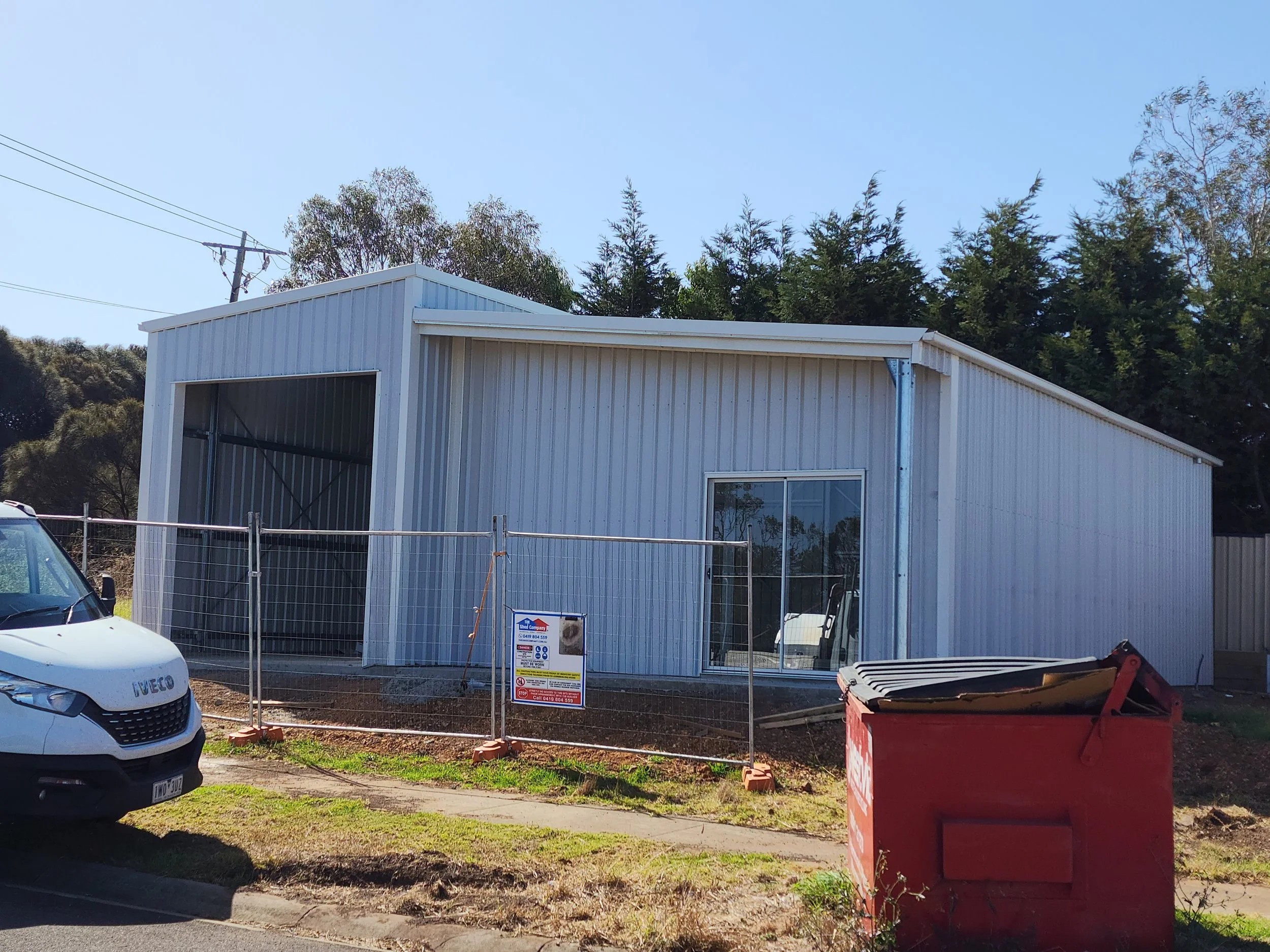 A shed with metal siding, a large open garage door, and a sliding glass door.