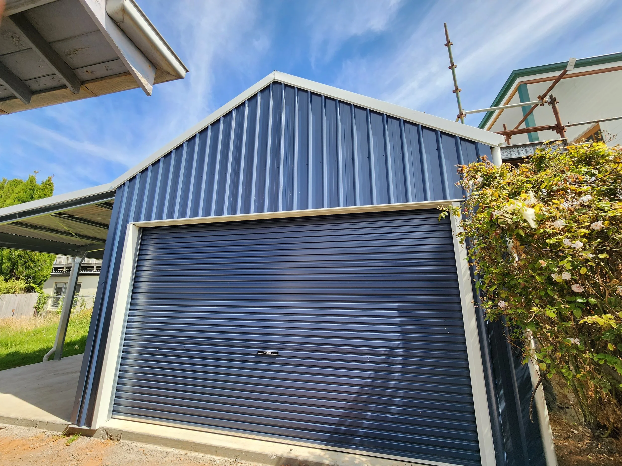 Blue metal sheds with a roll-up garage door built by M&C Sheds