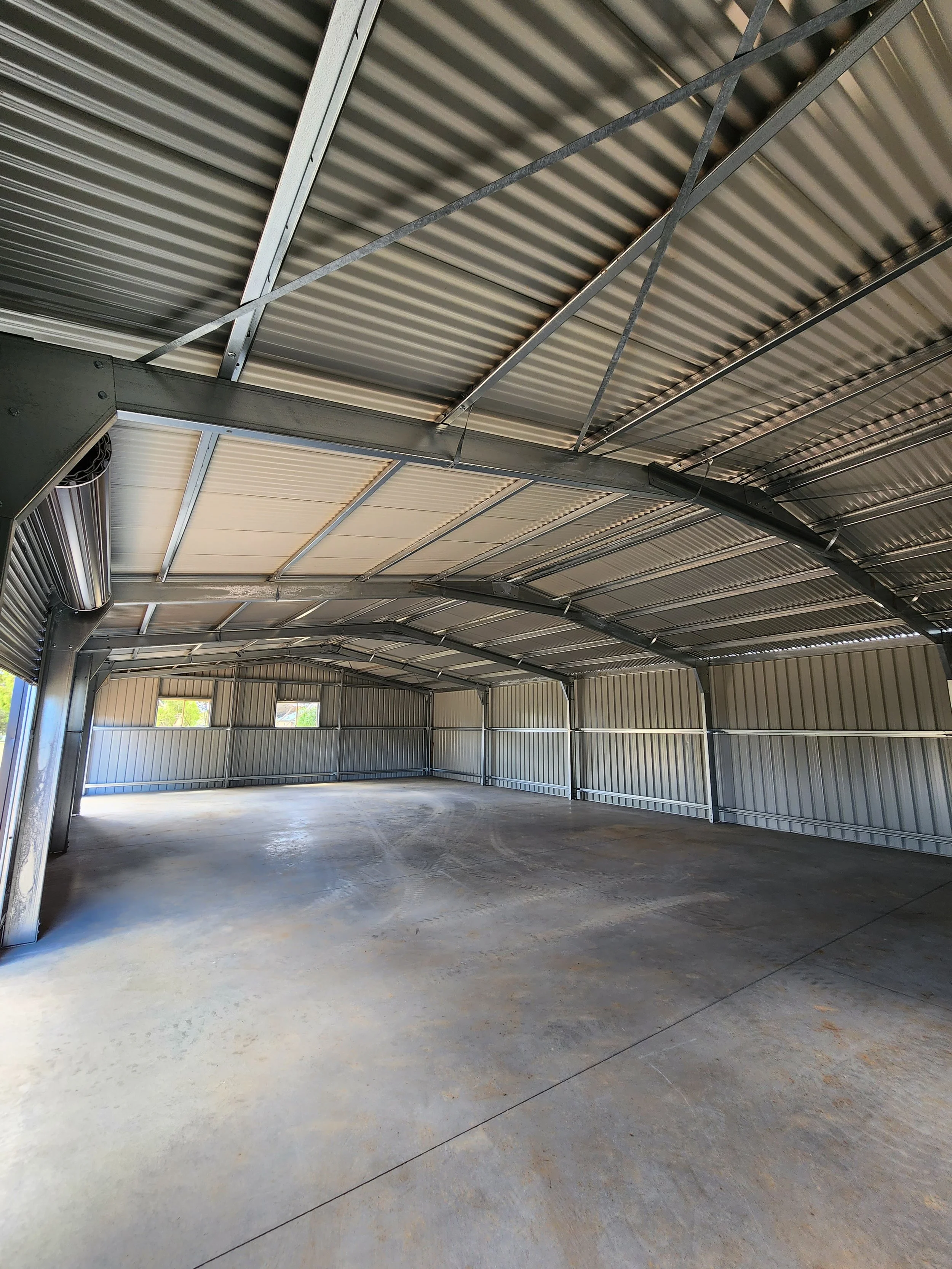 Empty metal carport shed with a concrete floor and metal walls and ceiling, built by M&C Sheds
