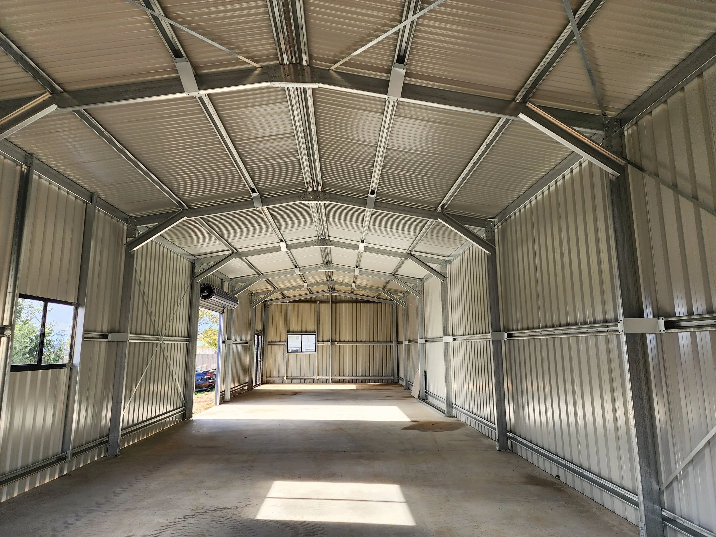 Empty metal warehouse storage shed with windows and concrete floor, built by M&C Sheds