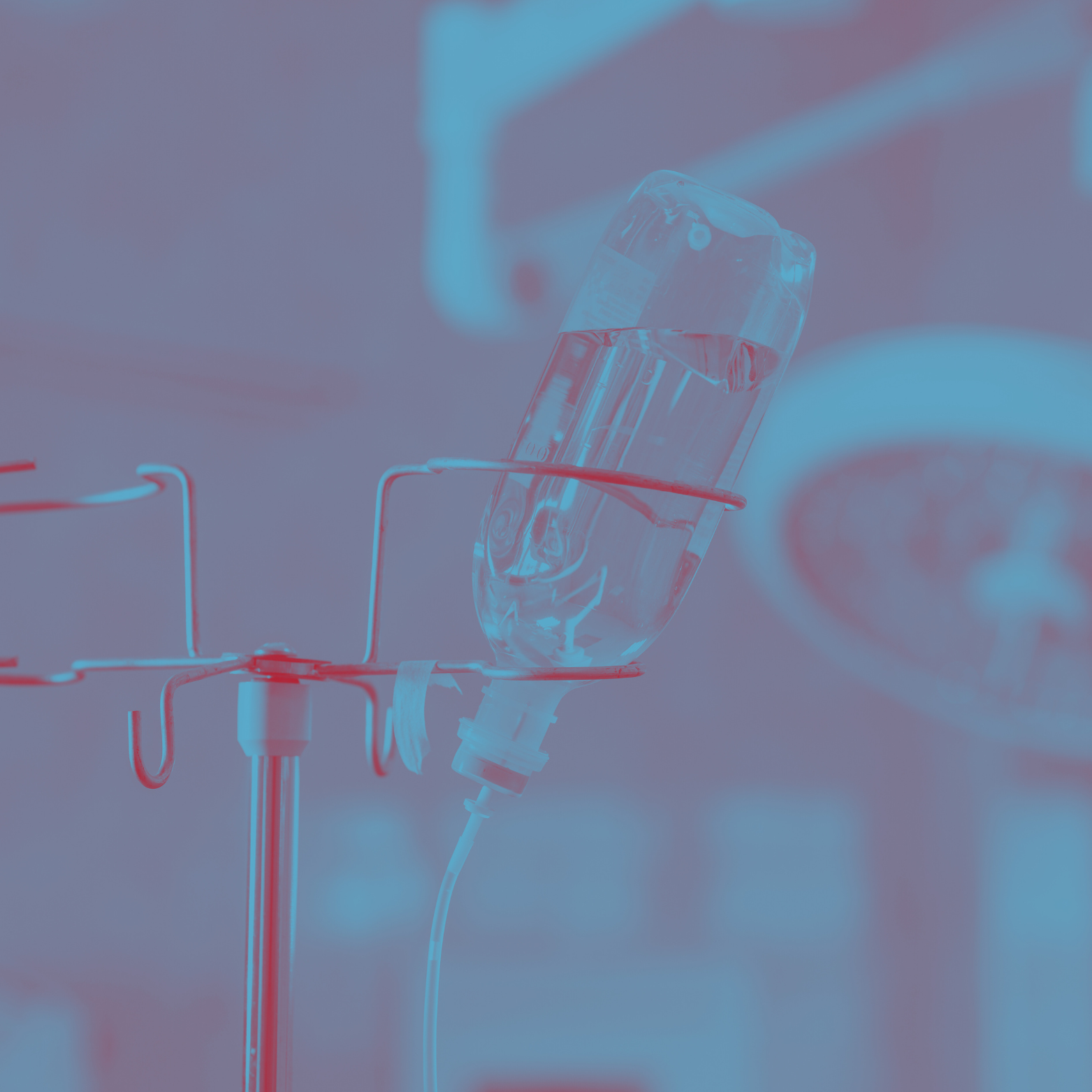 Medical IV drip with a bag of clear liquid hanging on a metal stand in a clinical setting.