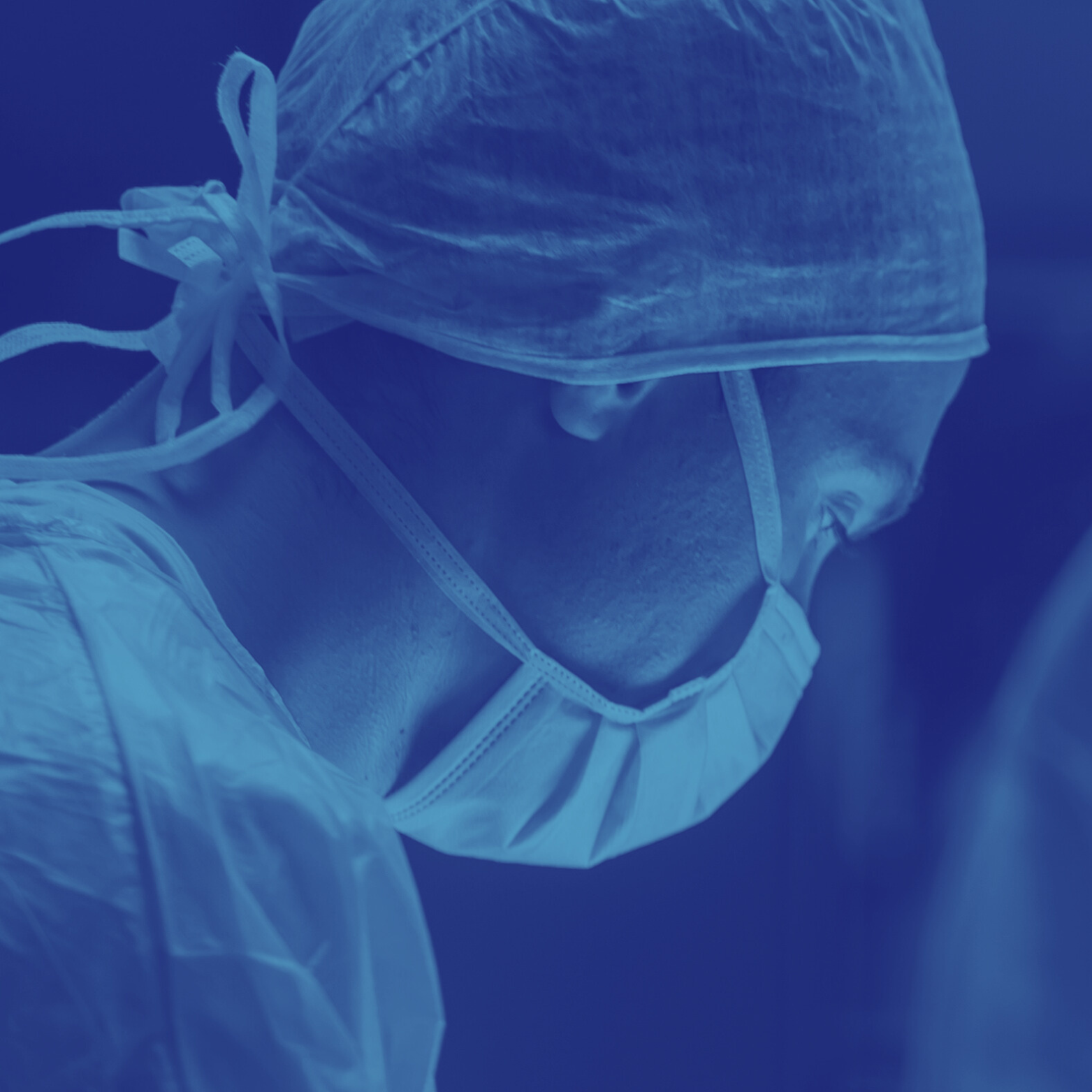 Medical professional wearing surgical cap, mask, and gown in a clinical setting, focusing on a task.