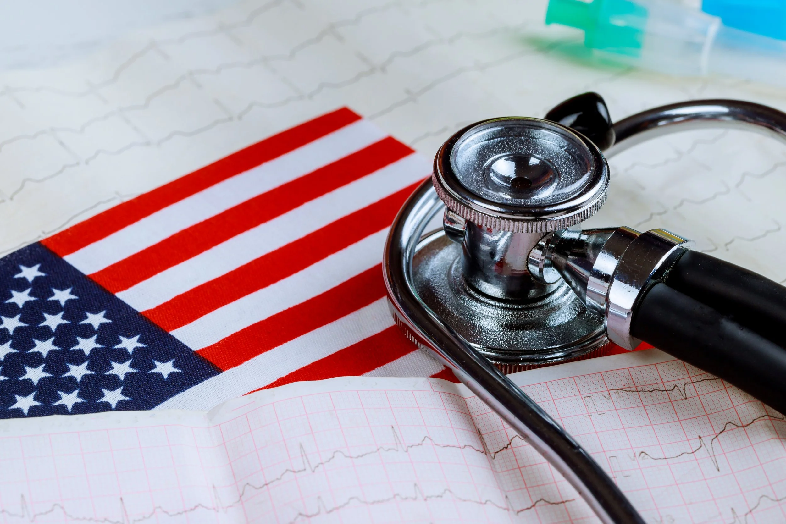 A stethoscope resting on an American flag, with an electrocardiogram (EKG) paper underneath.