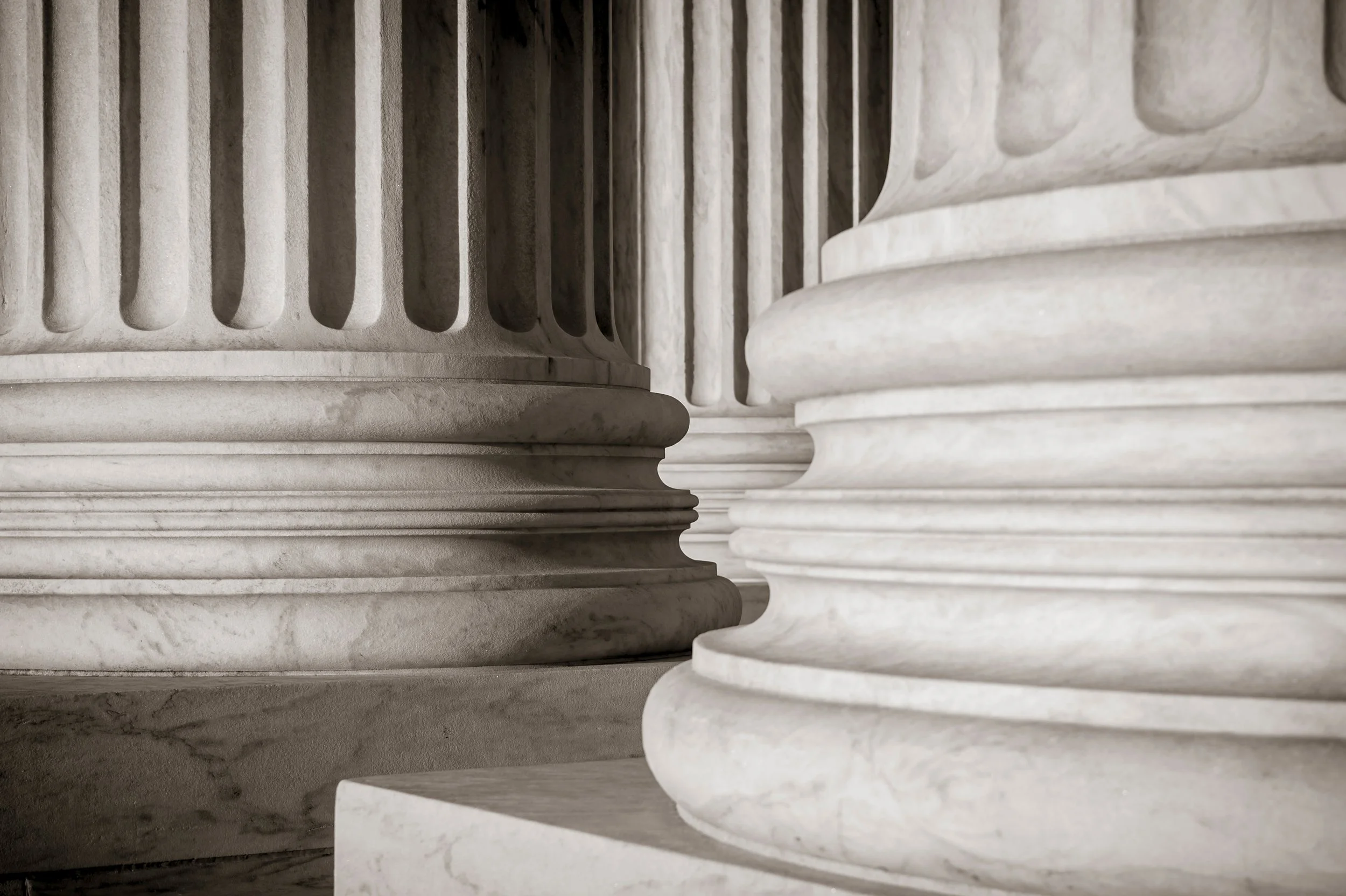 Close-up of marble columns showing detailed fluted and rounded bases in a classical architectural style.