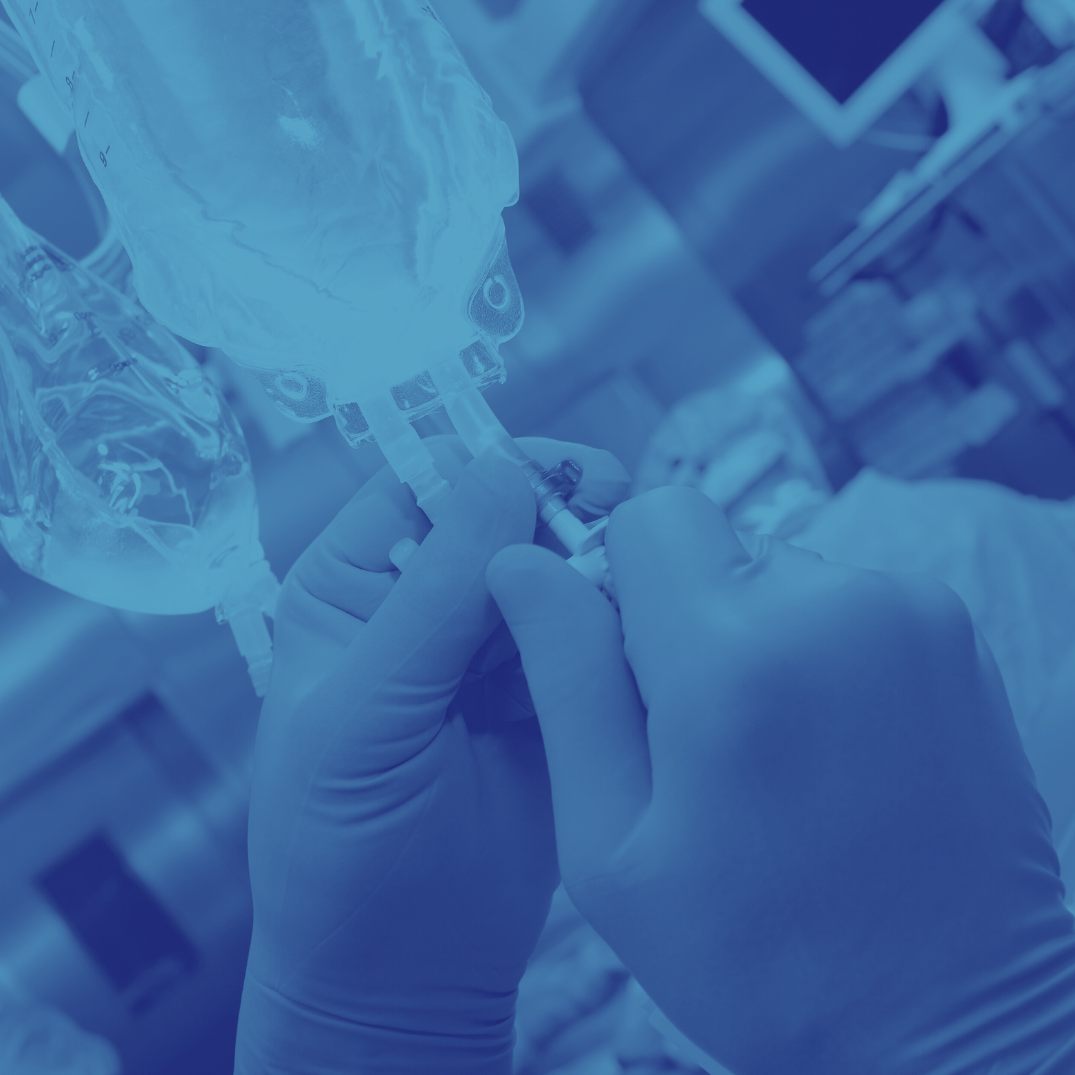 A healthcare worker wearing gloves prepares a syringe for vaccination with a large medical IV bag nearby, in a clinical setting.