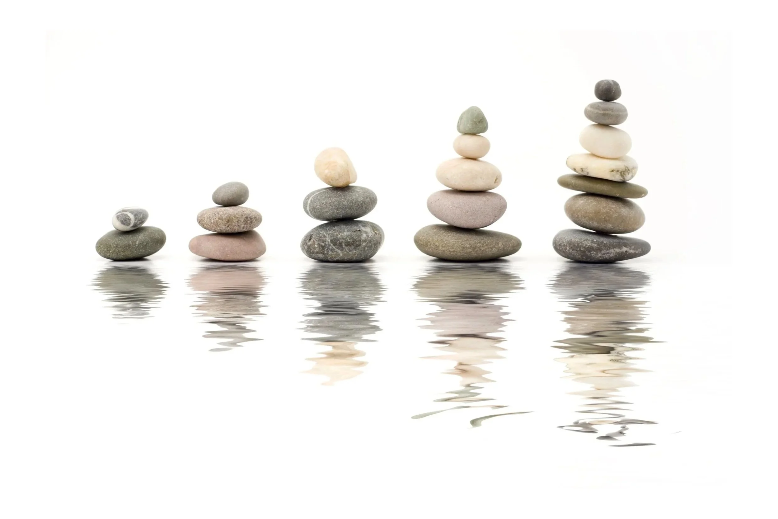 Five stacks of smooth, rounded stones arranged from smallest to largest, reflected in water, with a white background.