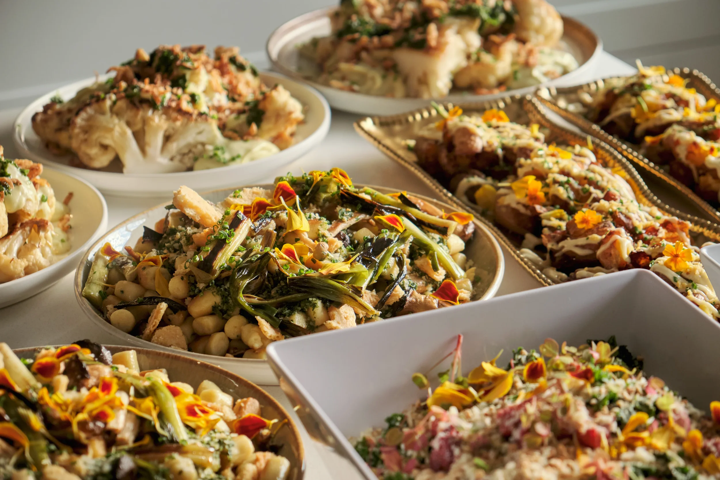 Assorted Indian street food dishes served in various bowls and plates, topped with colorful garnishes and edible flowers.