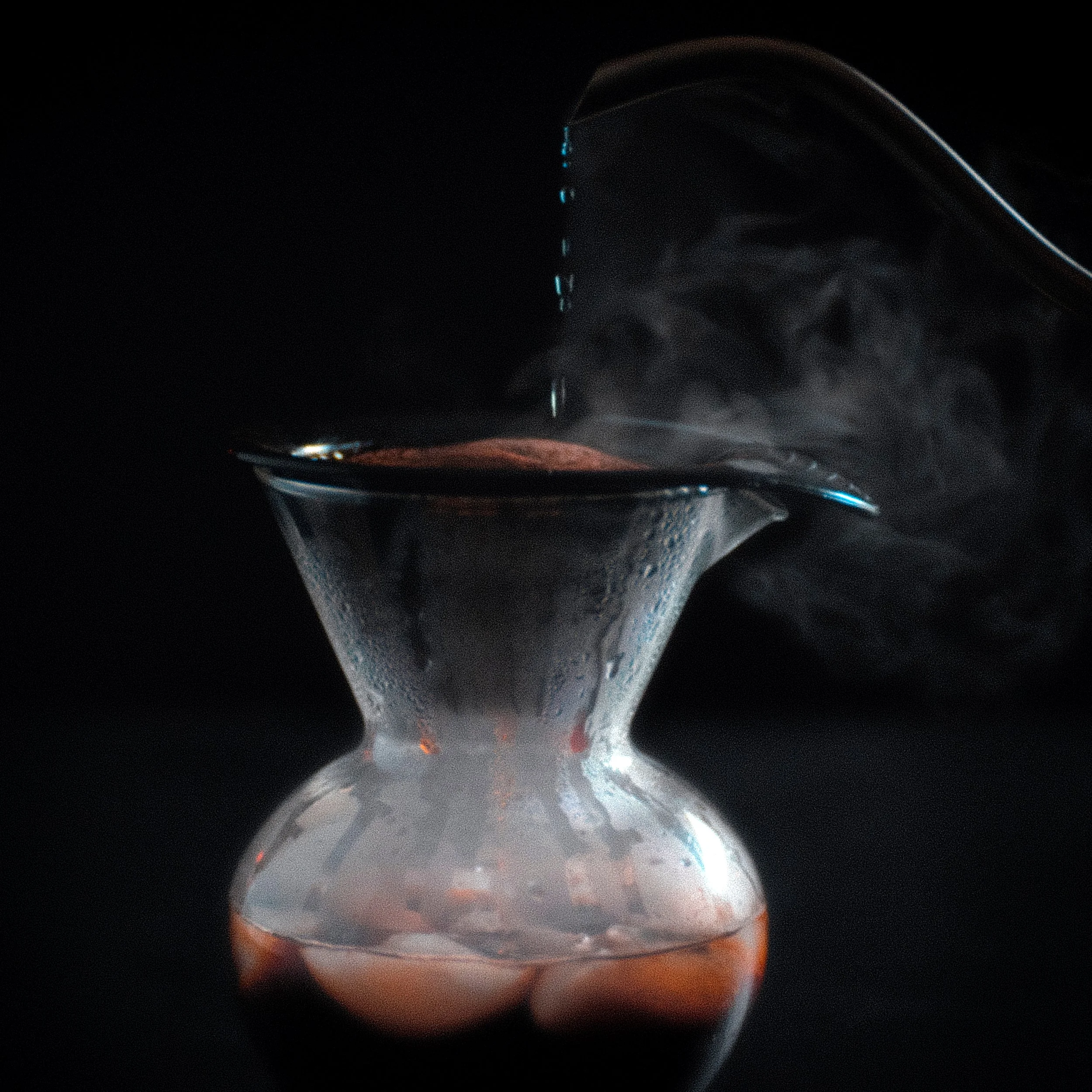 Close-up of a glass with water droplets and condensation on the outside, with a dark background.