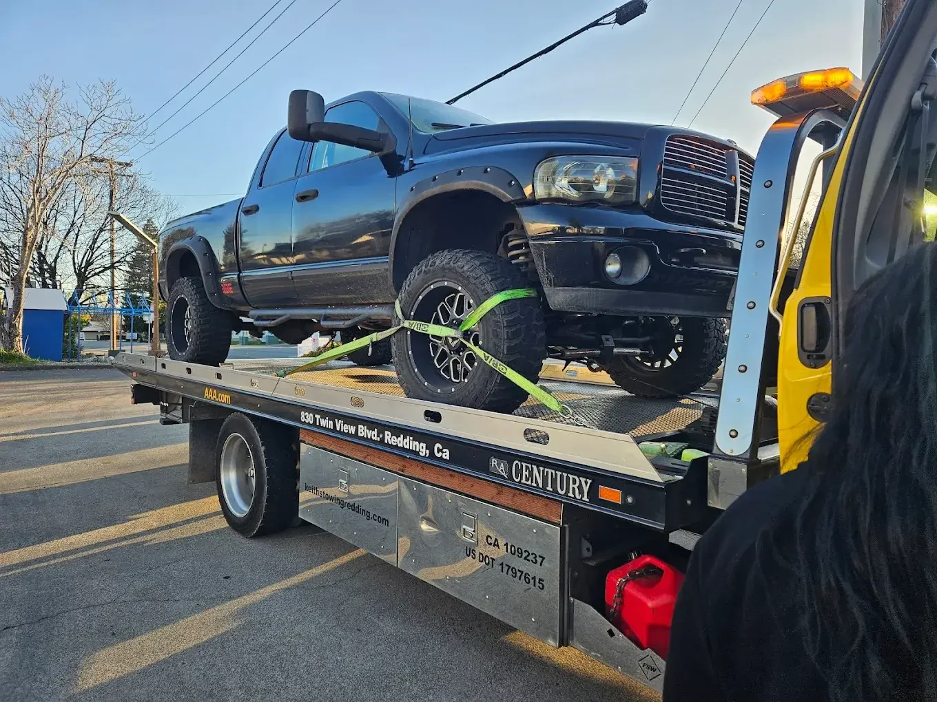Black pickup truck secured on a flatbed tow truck.