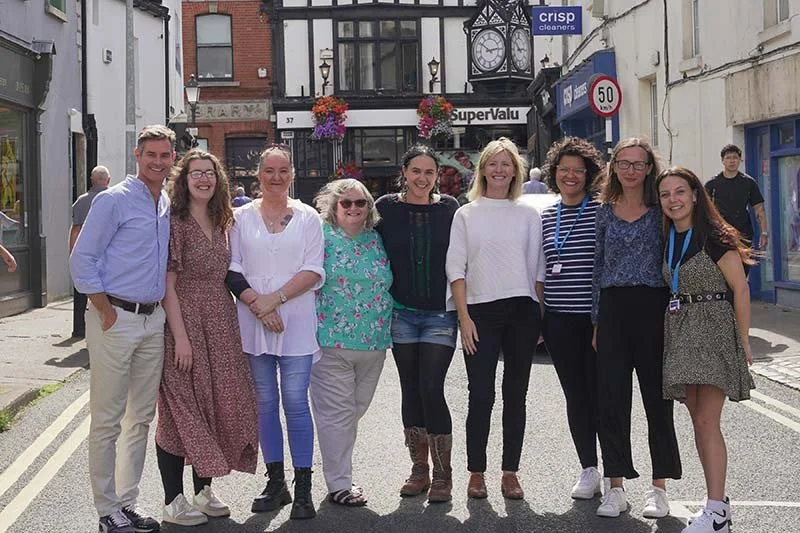 Group of nine people standing on a city street, smiling for a photo.