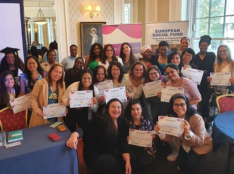 Group of women posing with certificates at a formal event in a decorated room with a European Social Fund banner in the background.
