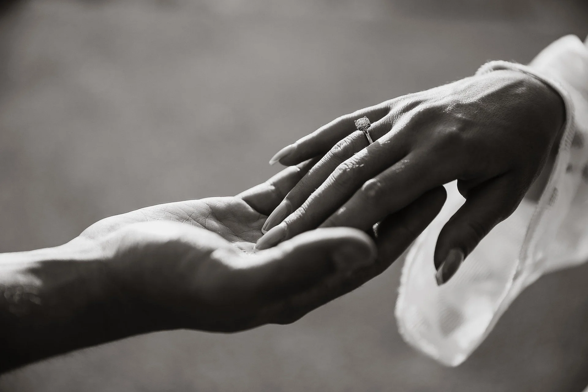 Close-up of a romantic proposal moment showing hands touching and an engagement ring