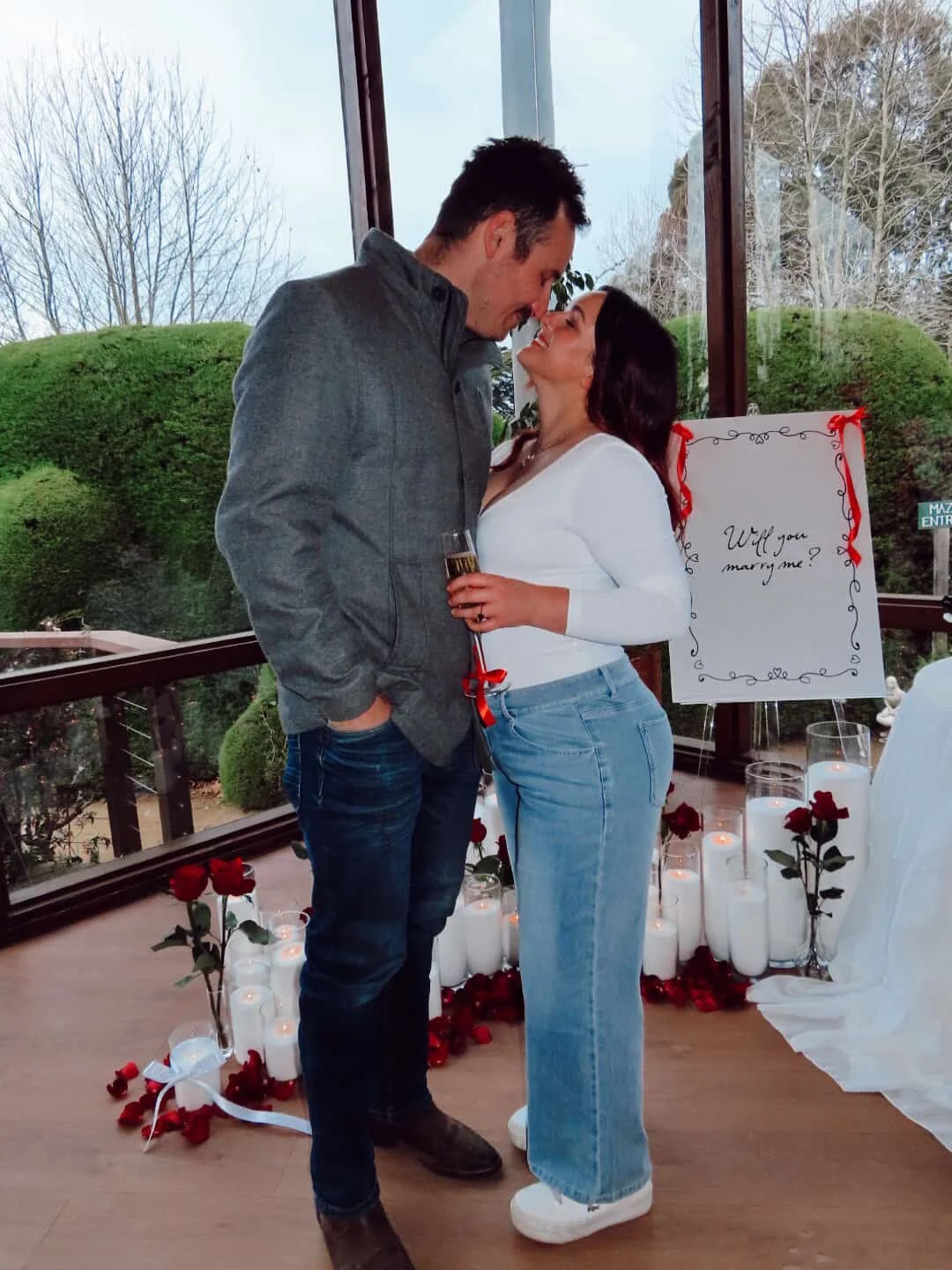 Balcony proposal setup with candlelight, roses, and a couple celebrating a proposal moment