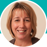 Close-up of a smiling woman with short, light brown hair, wearing a white top.