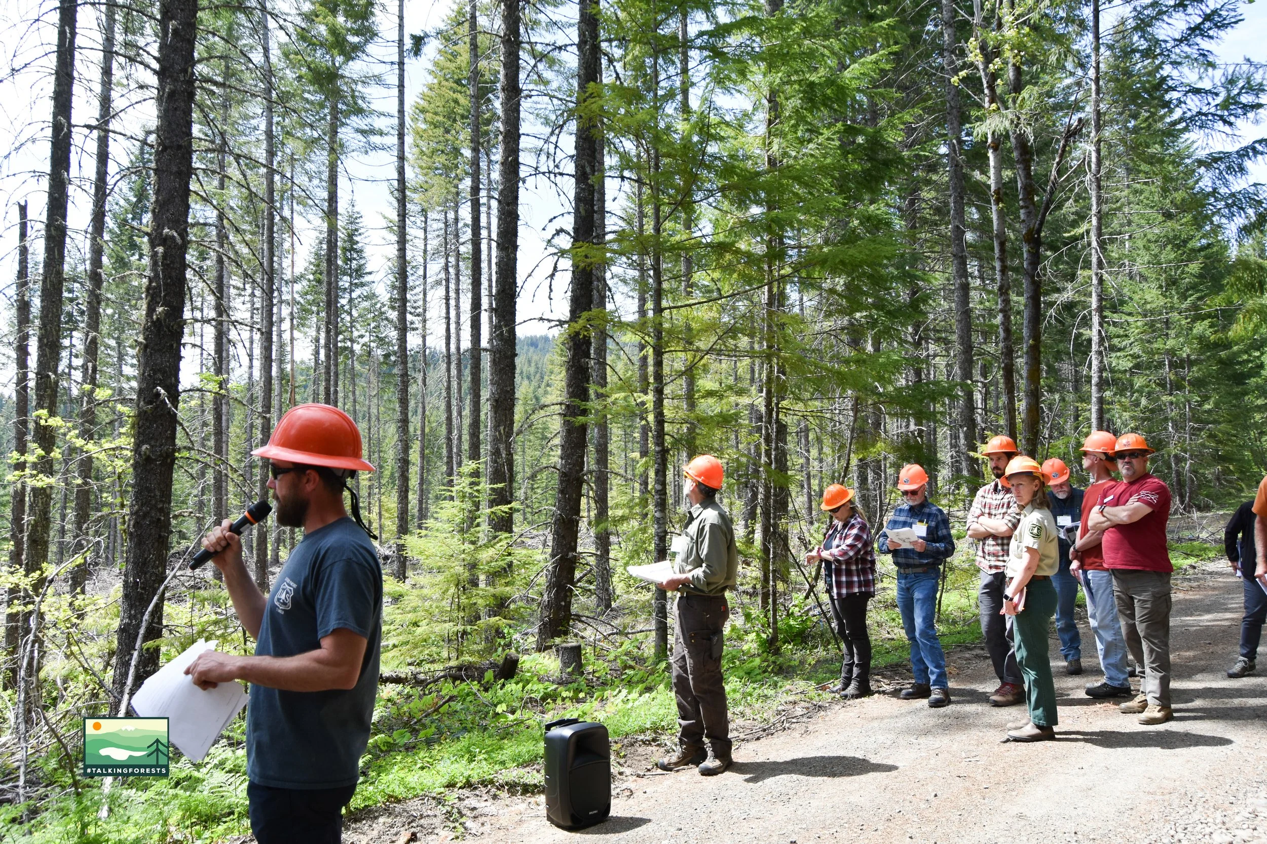 Scenic landscape with mountains surrounding a lake, rolling hills, and sparse vegetation under a cloudy sky.