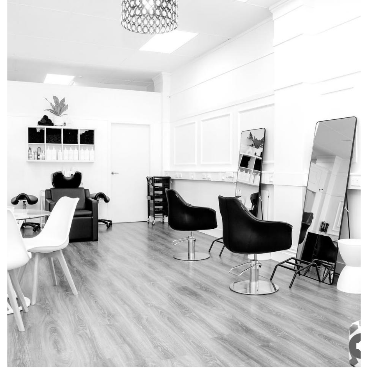 Black and white photo of a hair salon with salon chairs, mirrors, and styling stations.