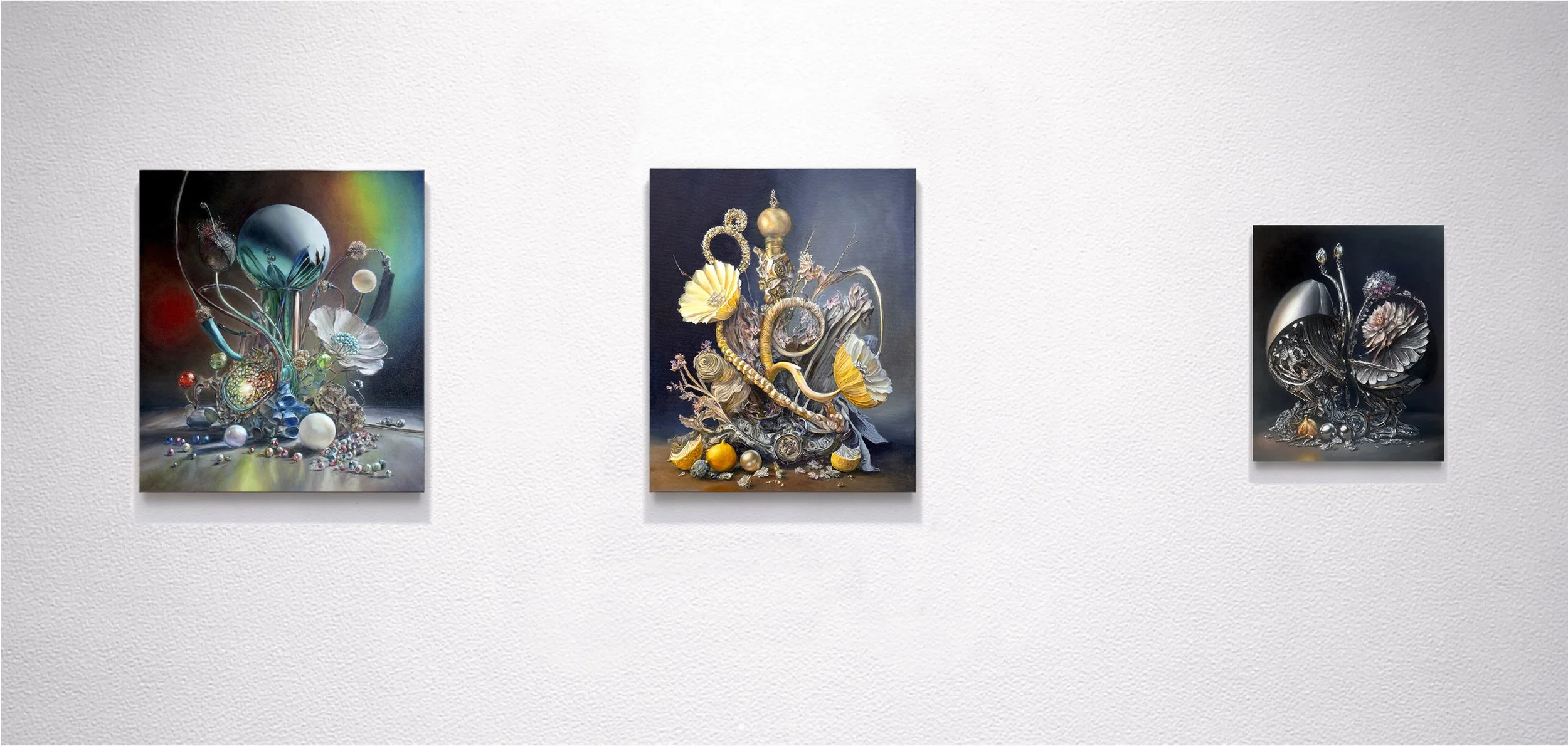 Three abstract paintings displayed on a white gallery wall, featuring intricate sculptures and textures with a mix of shiny, metallic, and colorful elements.