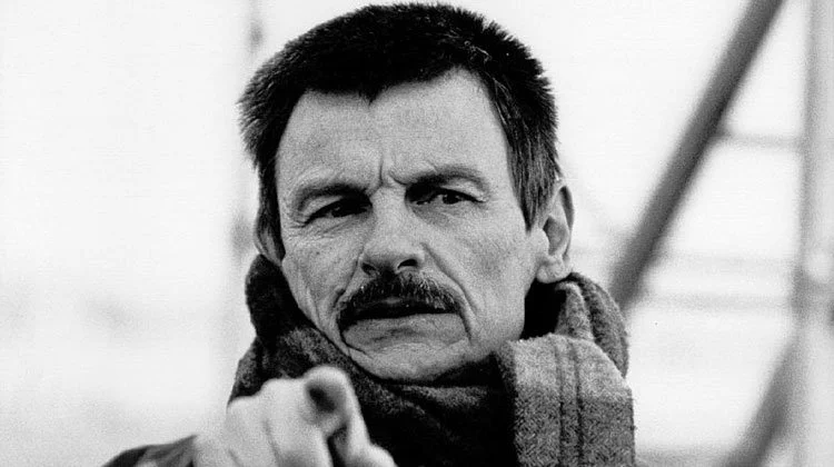 Black and white photo of Tarkovsky man with a mustache pointing his finger forward, looking serious.