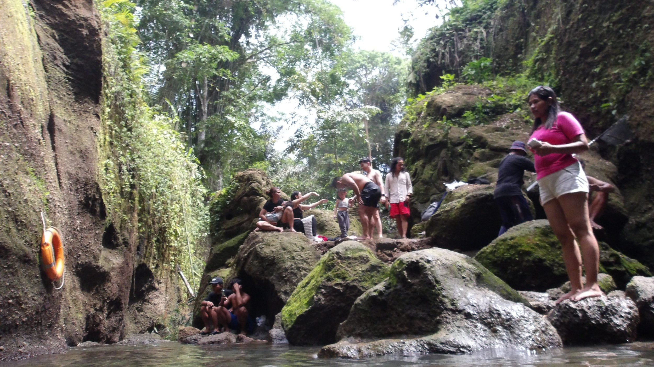 Group of people exploring a rocky stream in a lush forest