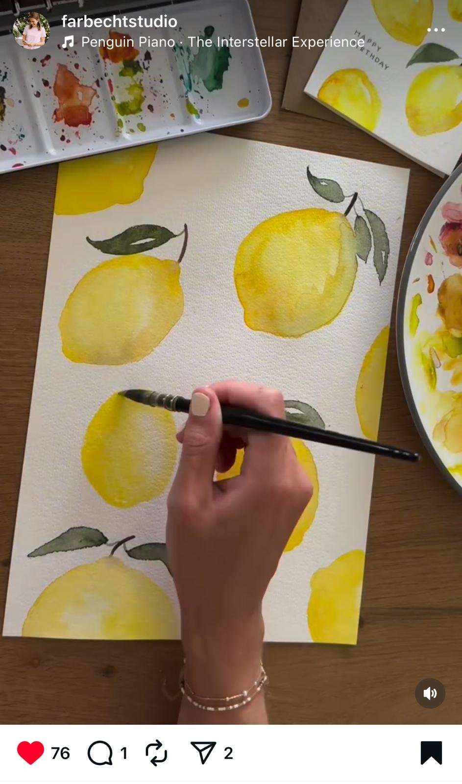 Eine Person malt mit Aquarellfarben gelbe Zitronen mit grünen Blättern. Es sind mehrere Zitronen auf einem weißen Wasserpapier. Paletten mit Wasserfarben sind an der Seite zu sehen.