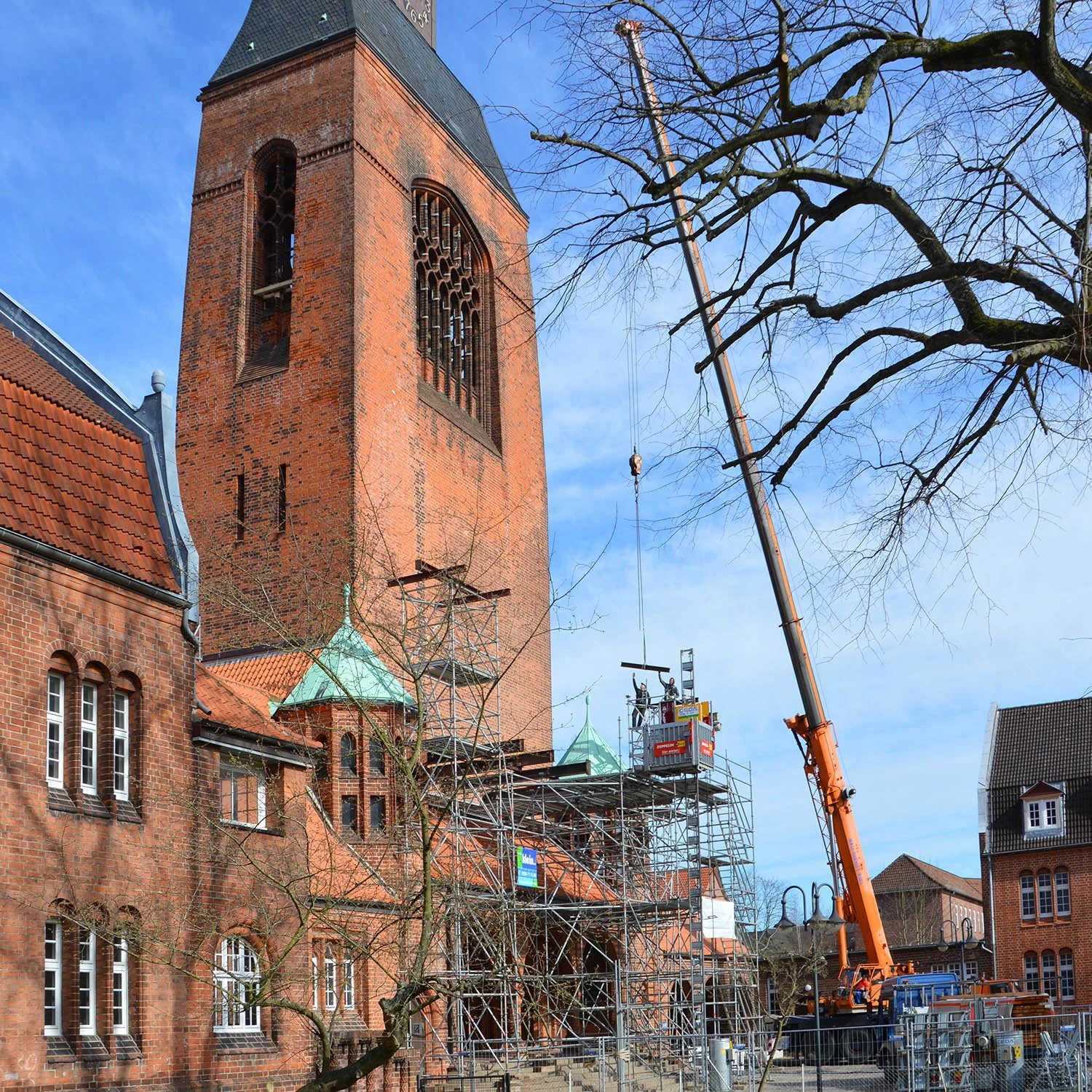 Der Wiederaufbau einer alten Kirche mit Gerüst und Kran. Das Kirchengebäude besteht aus rotem Backstein, mit hohen Fenstern und einer Turmspitze, die noch saniert wird.