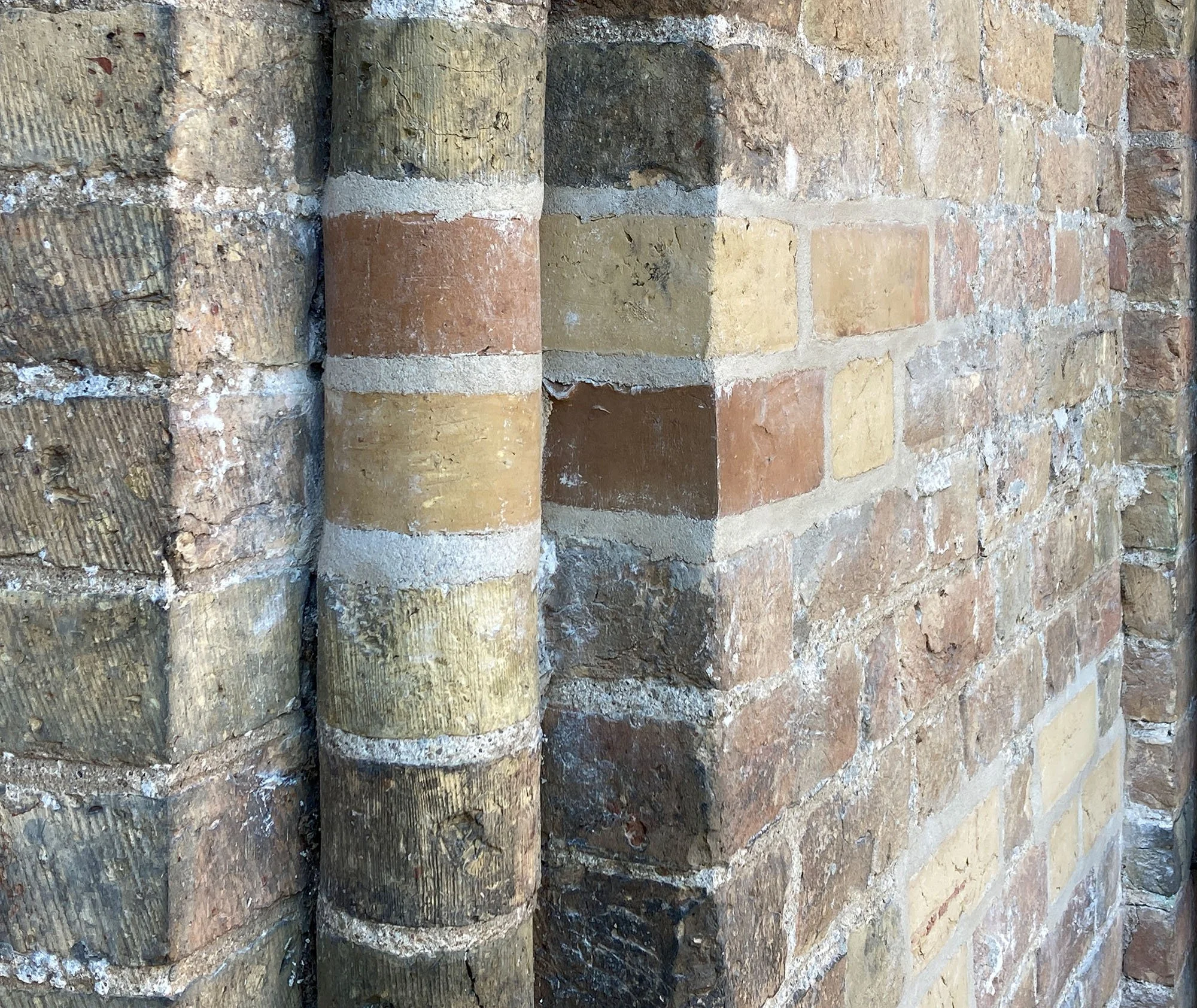 Nahaufnahme einer Ecke einer Ziegelmauer mit unterschiedlichen Ziegelarten und Farben.