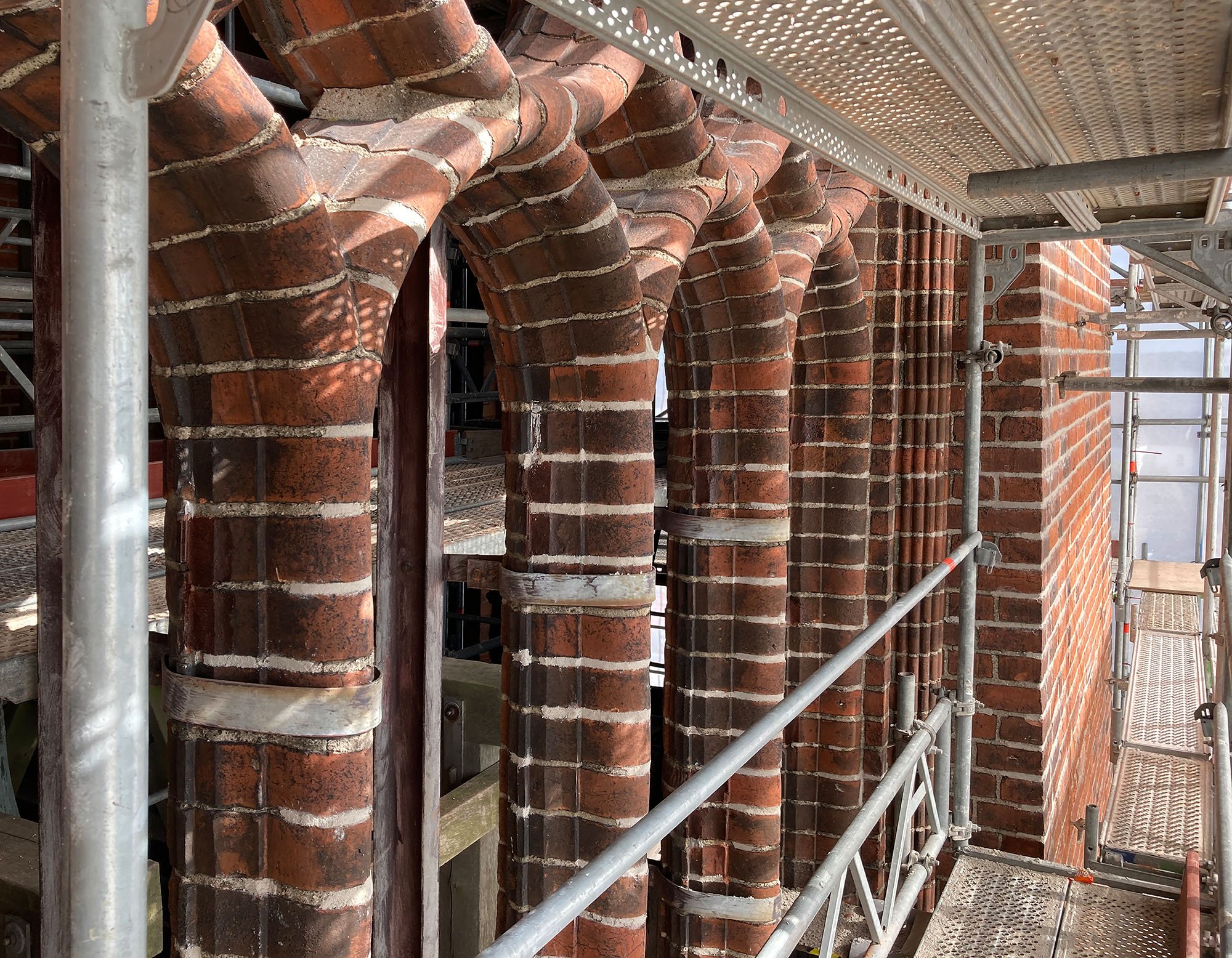 Eine Baugerüststruktur mit rotem Ziegelmauerwerk und mehreren Ziegelbögen, die Teil eines historischen Gebäudes sein könnten.