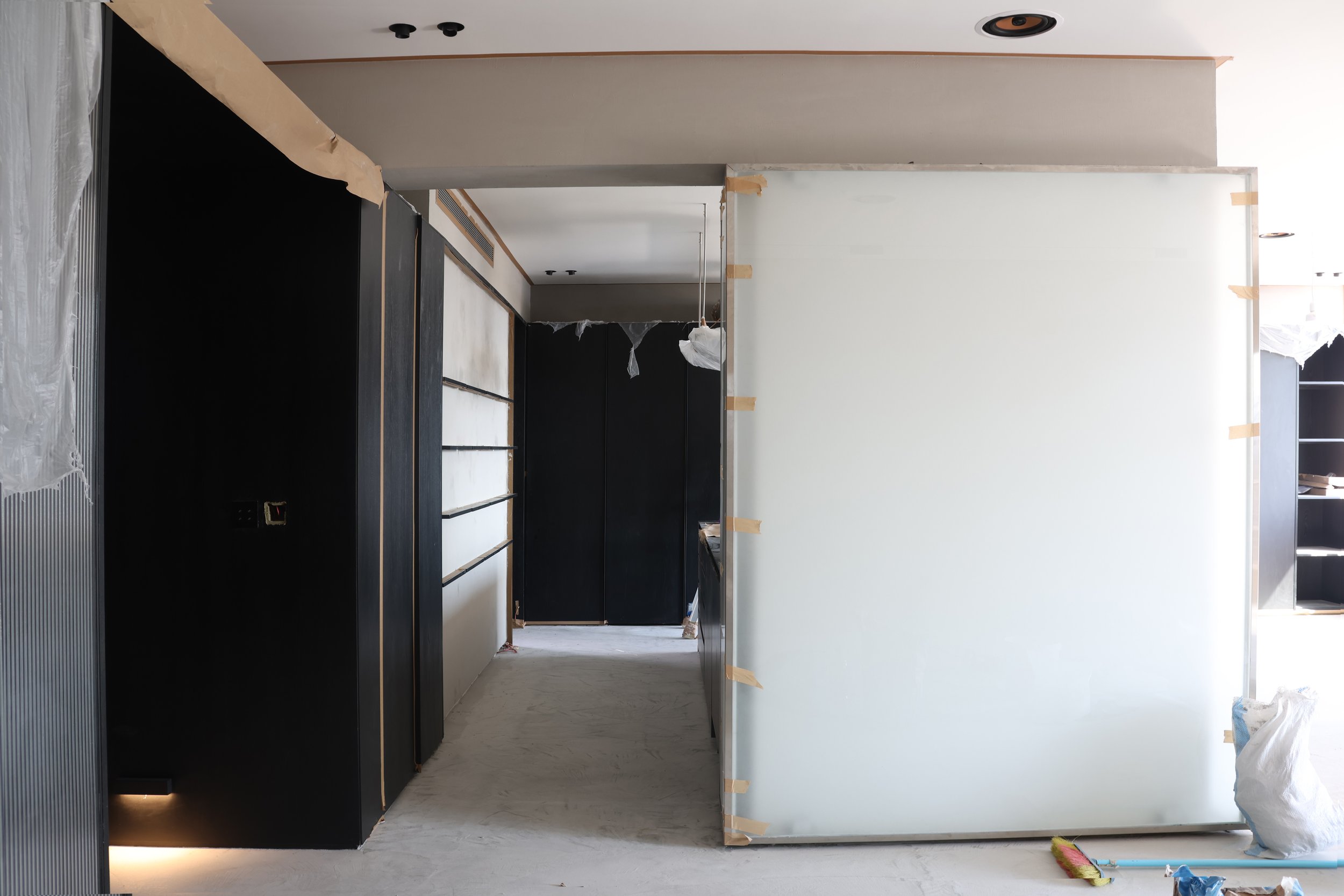 Interior of a building under construction with black and white walls, construction materials, and partially installed fixtures.