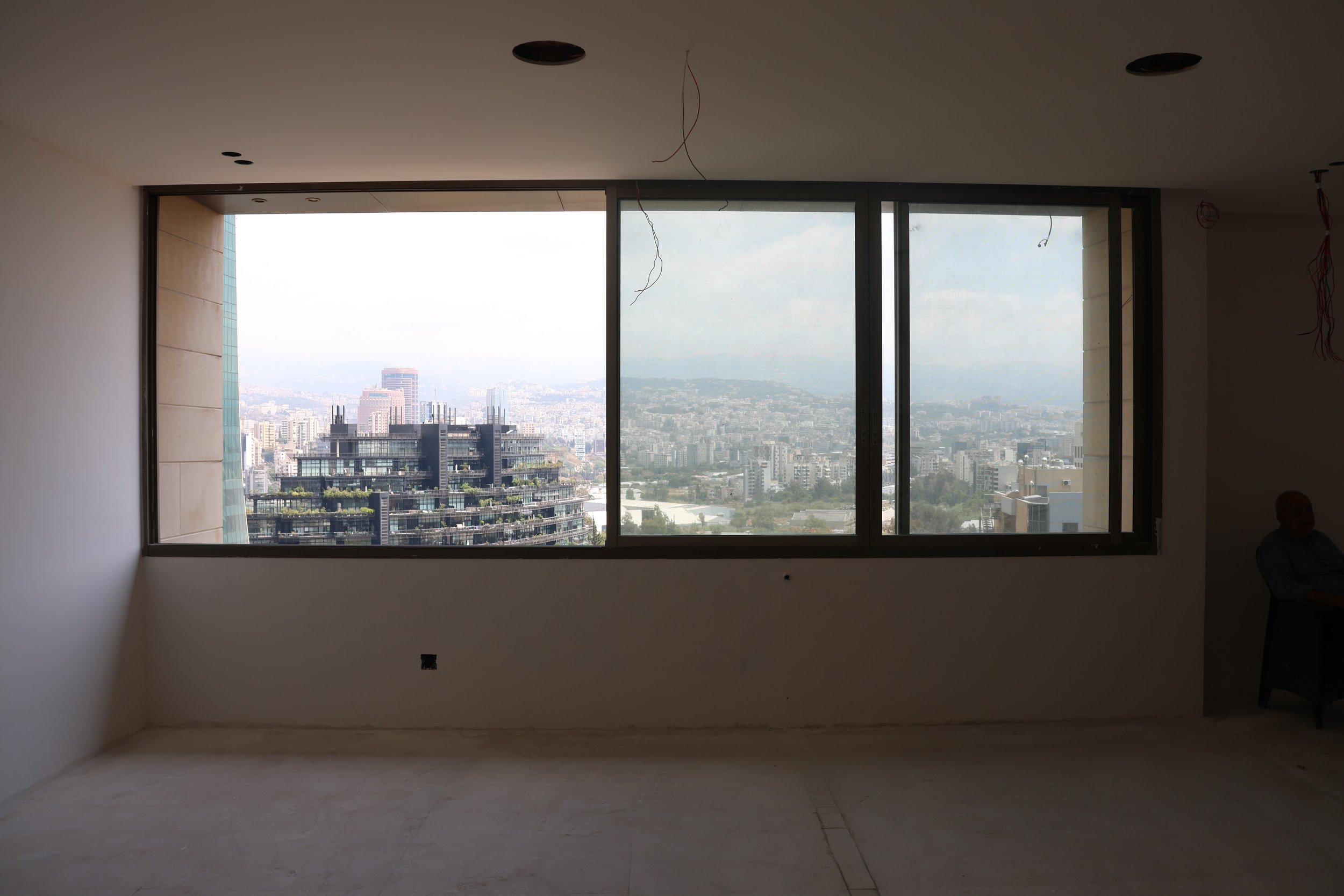 Interior of an unfinished room with a large window showing a city skyline.