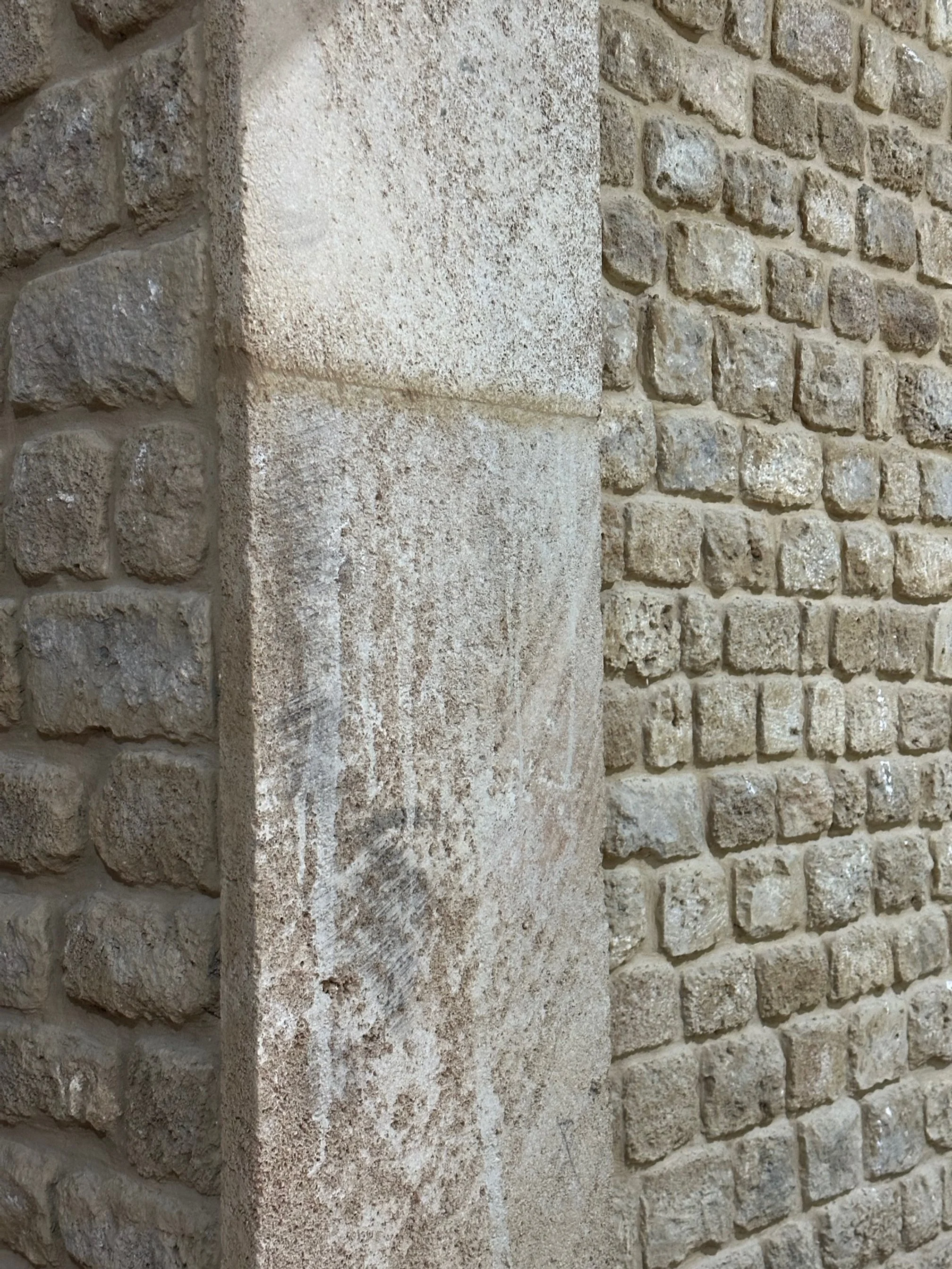Close-up of a stone wall with rough, uneven bricks and a corner of smooth, rectangular stone block.