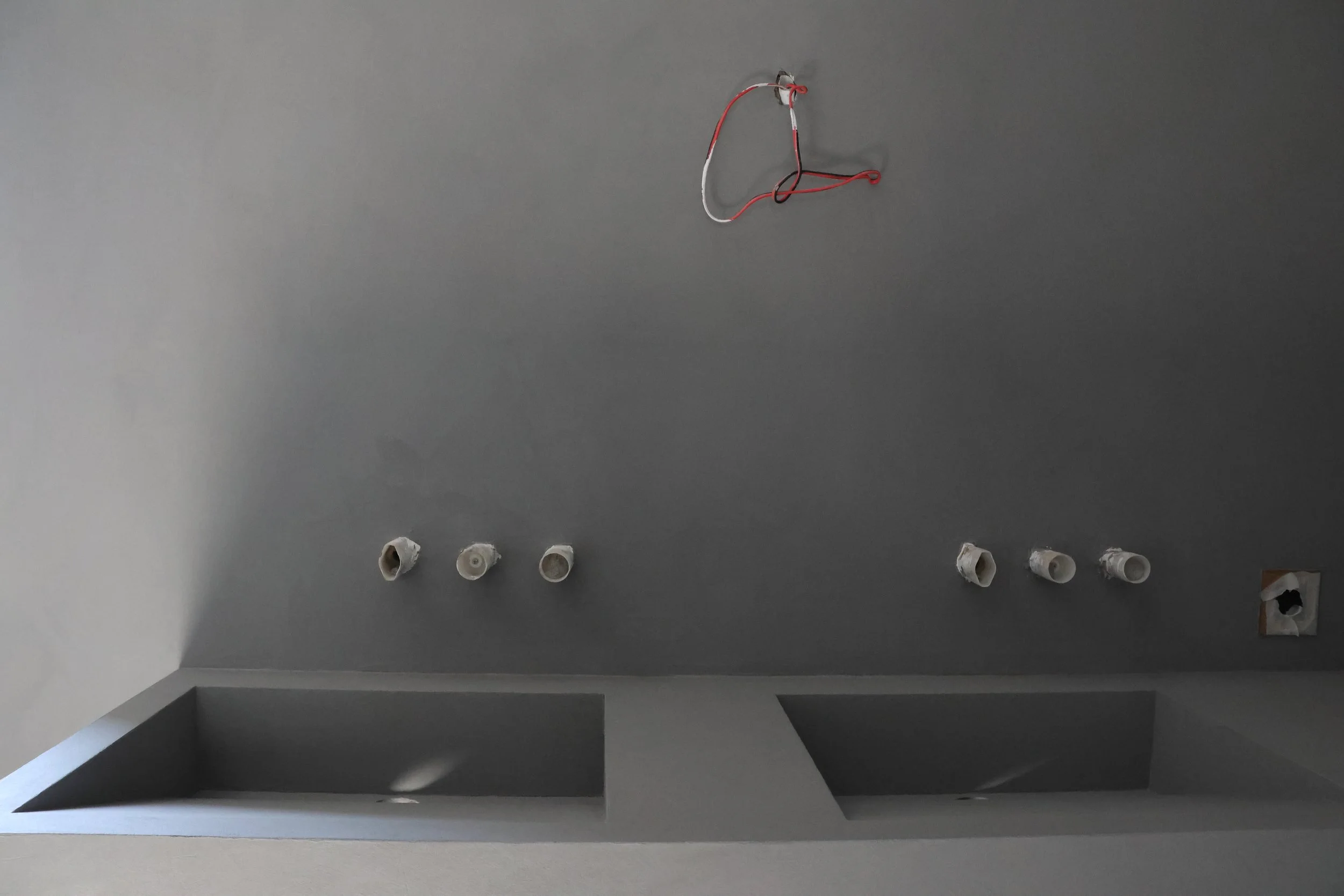 Ceiling with six light fixtures and red and white wires hanging, oval-shaped wall cutouts, and a small square opening at the bottom right.