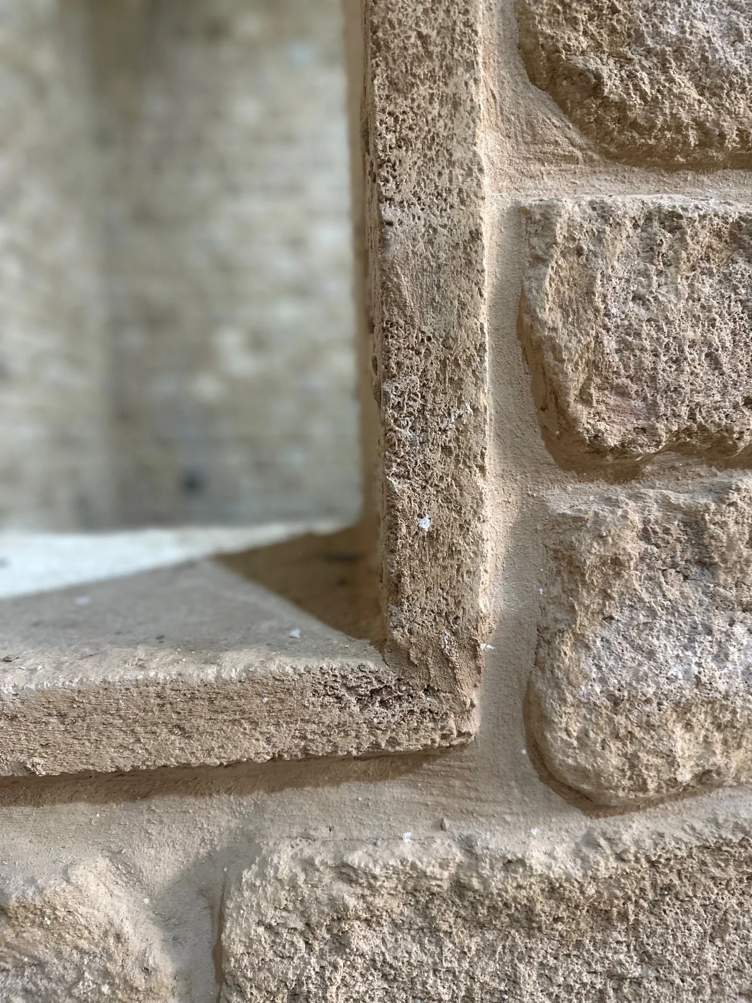 Close-up of a textured beige brick wall with a corner detail.