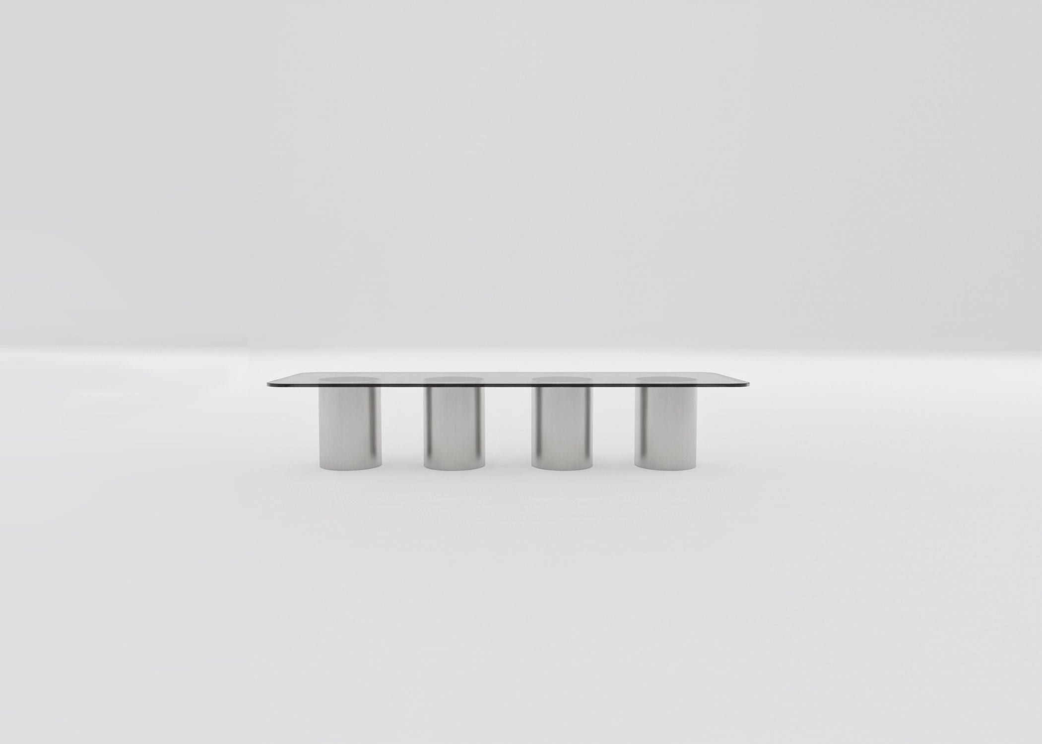 Modern rectangular table with a glass top and four cylindrical metal legs, set against a plain white background.