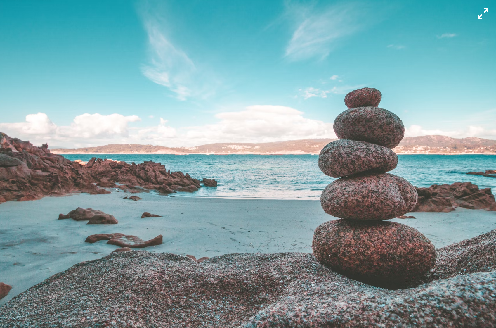 Un tas de pierres empilées sur une plage avec vue sur la mer et des montagnes en arrière-plan