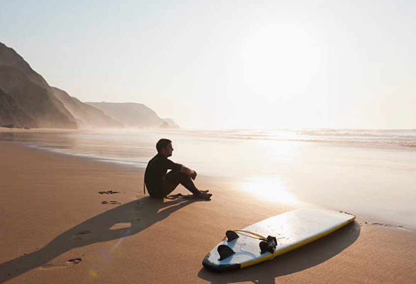 Surfeur au repos sur la plage bretonne, combinaison parfaite surf et rituel sauna après l'océan