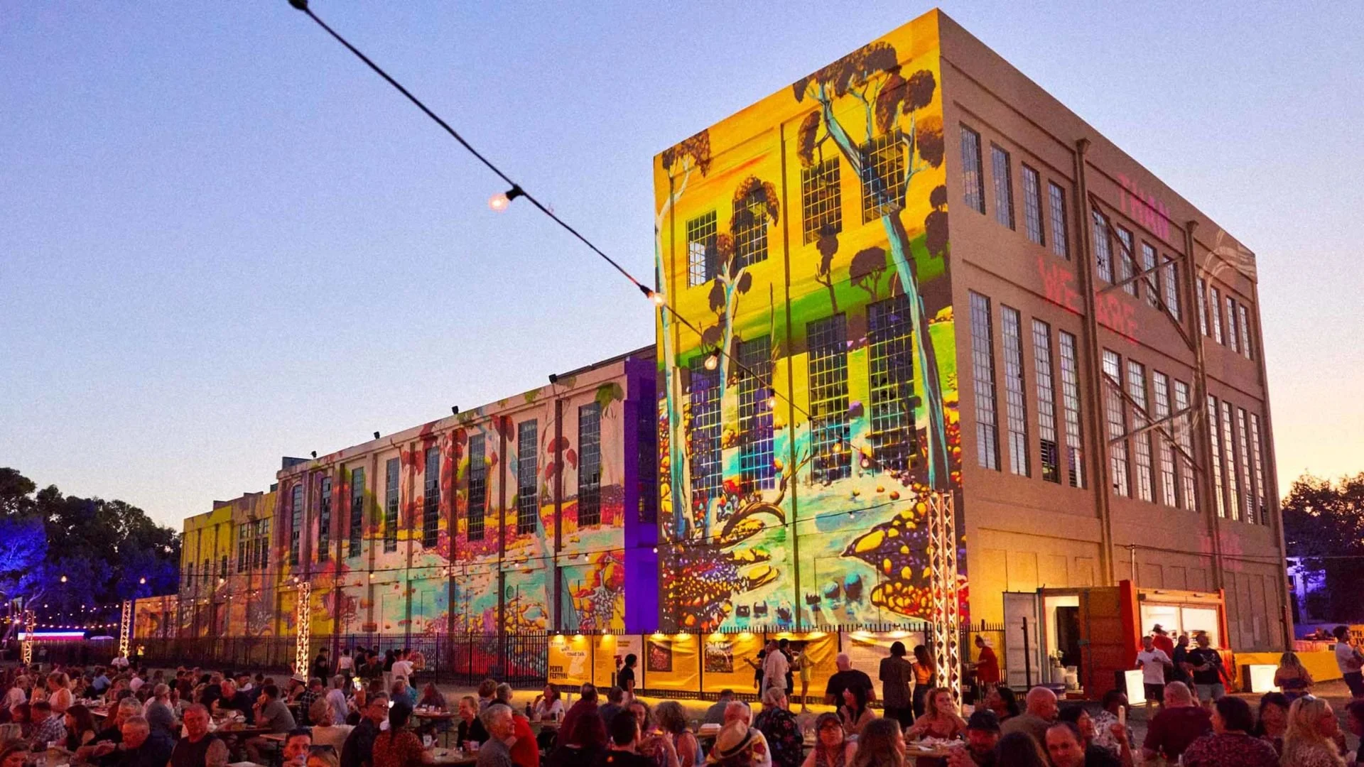 An image of an old warehouse with a light show being projected onto it.