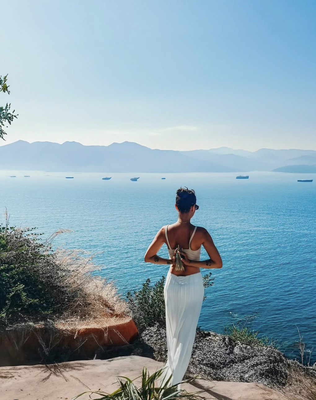 Woman on cliff by the ocean, scenic coastal view, mindfulness and wellness moment