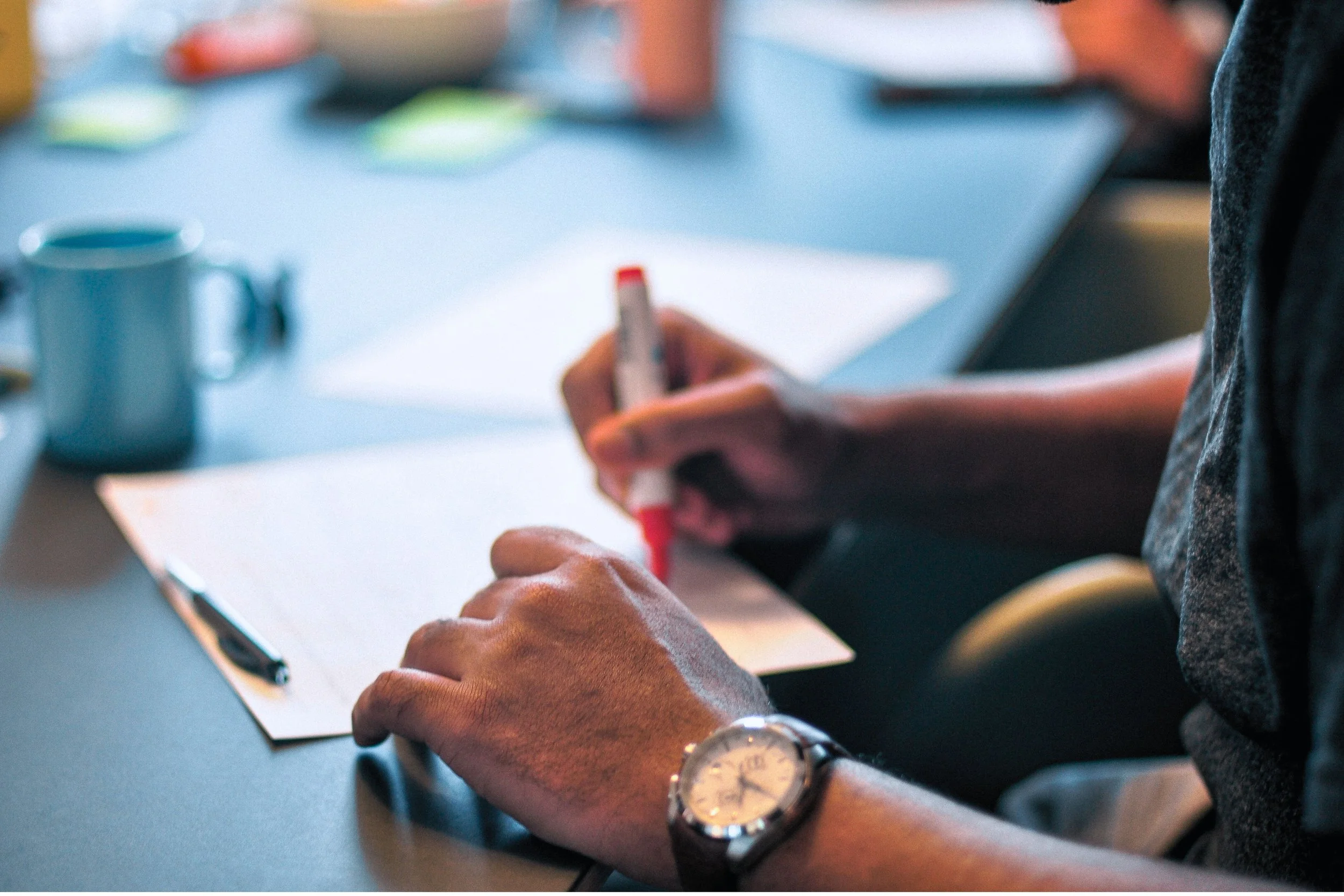 Hands on desk writing with red marker